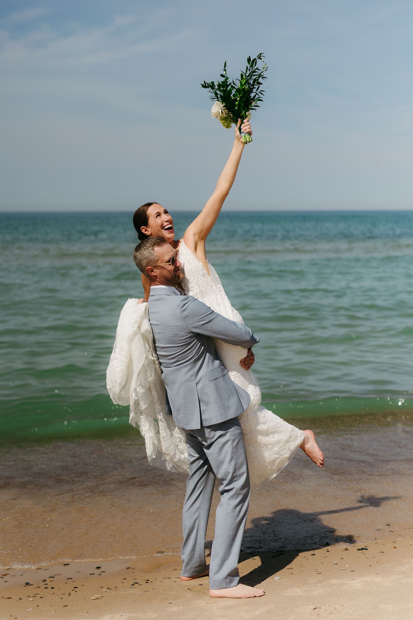 Bride and groom running along the shore of Lake Michigan during their elopement at Warren Dunes State Park