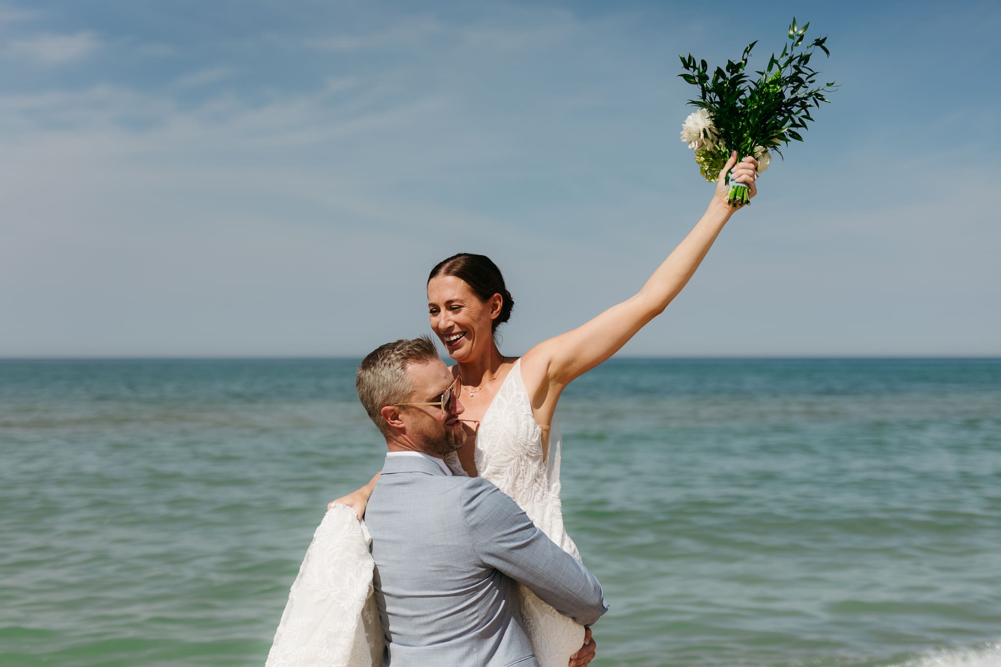 Bride and groom running along the shore of Lake Michigan during their elopement at Warren Dunes State Park