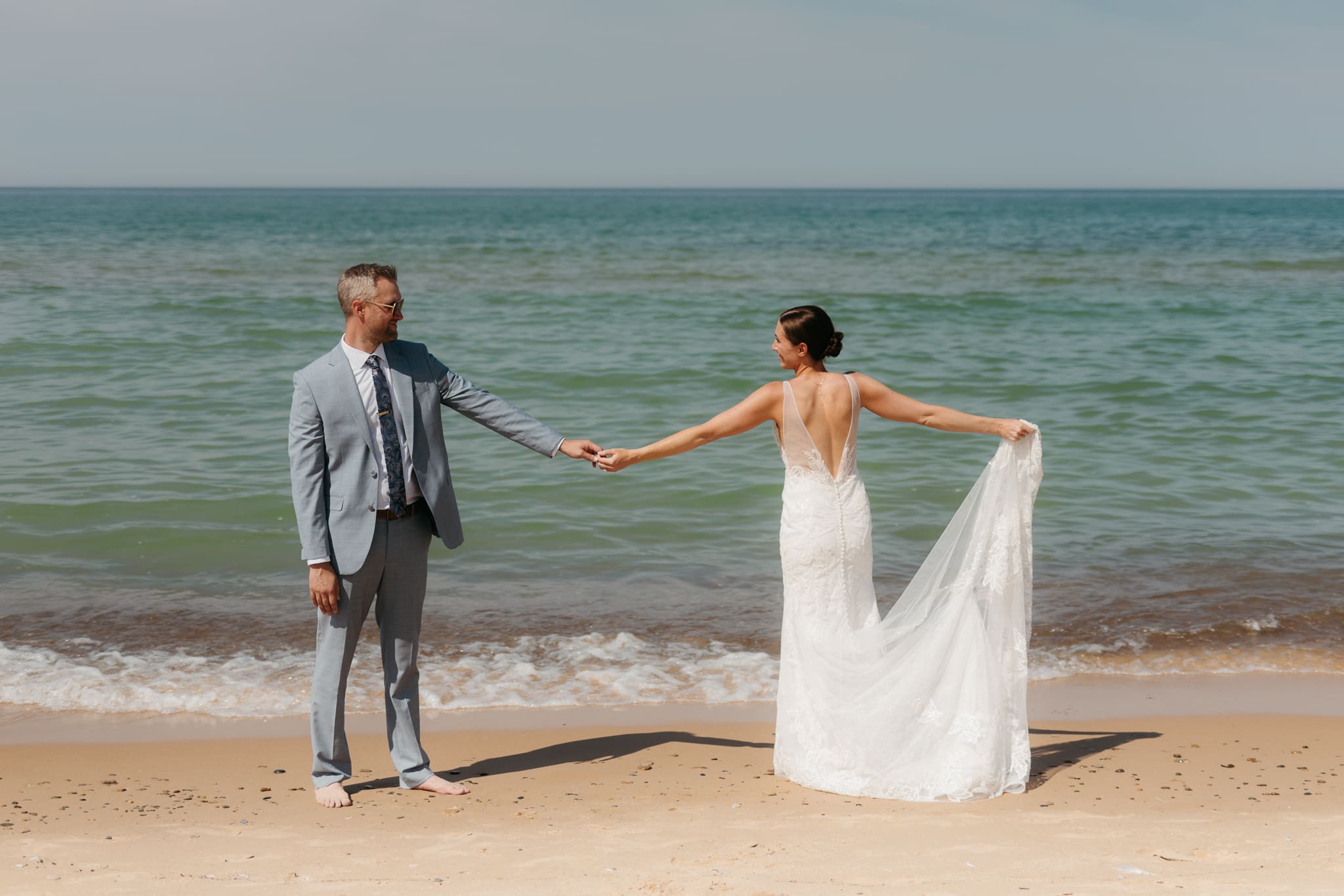 Bride and groom running along the shore of Lake Michigan during their elopement at Warren Dunes State Park