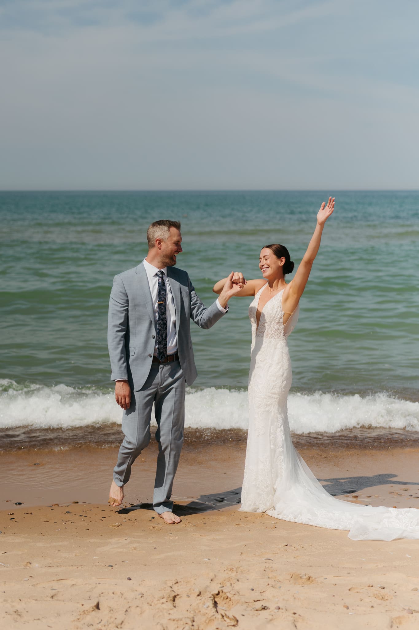 Bride and groom running along the shore of Lake Michigan during their elopement at Warren Dunes State Park