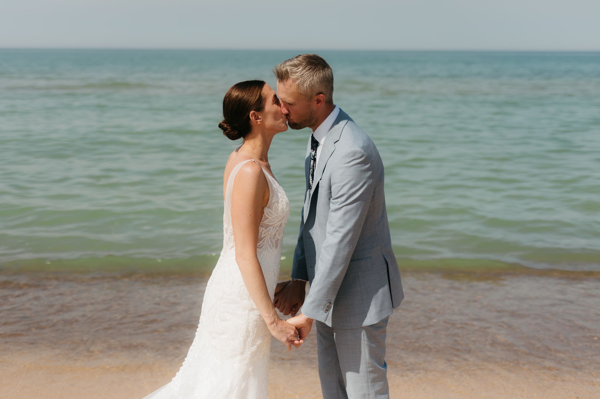 Bride and groom running along the shore of Lake Michigan during their elopement at Warren Dunes State Park