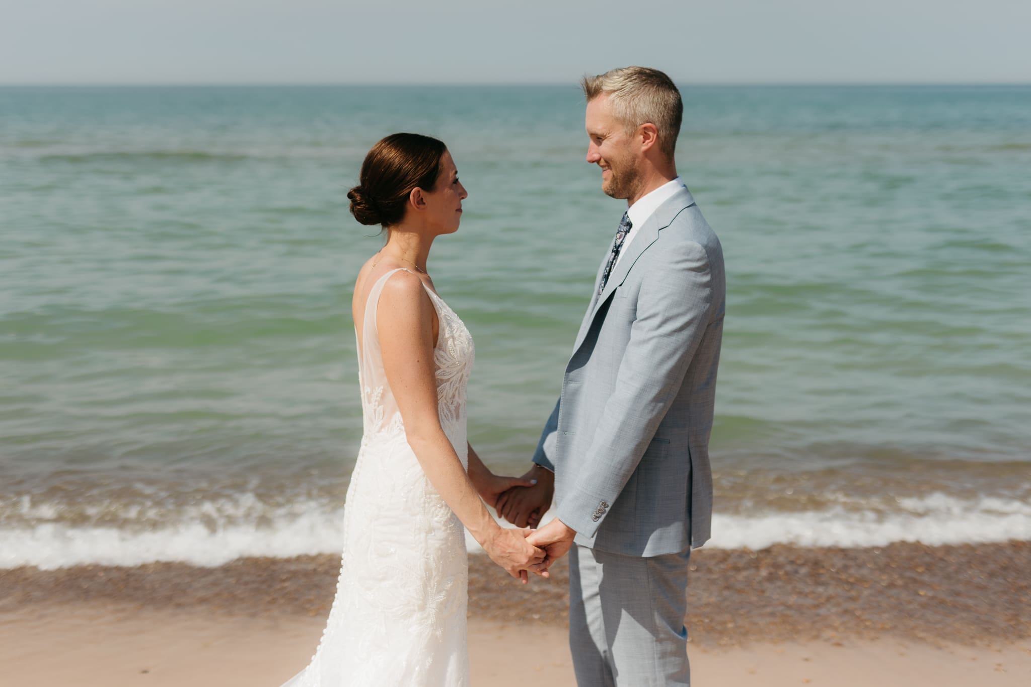 Bride and groom running along the shore of Lake Michigan during their elopement at Warren Dunes State Park