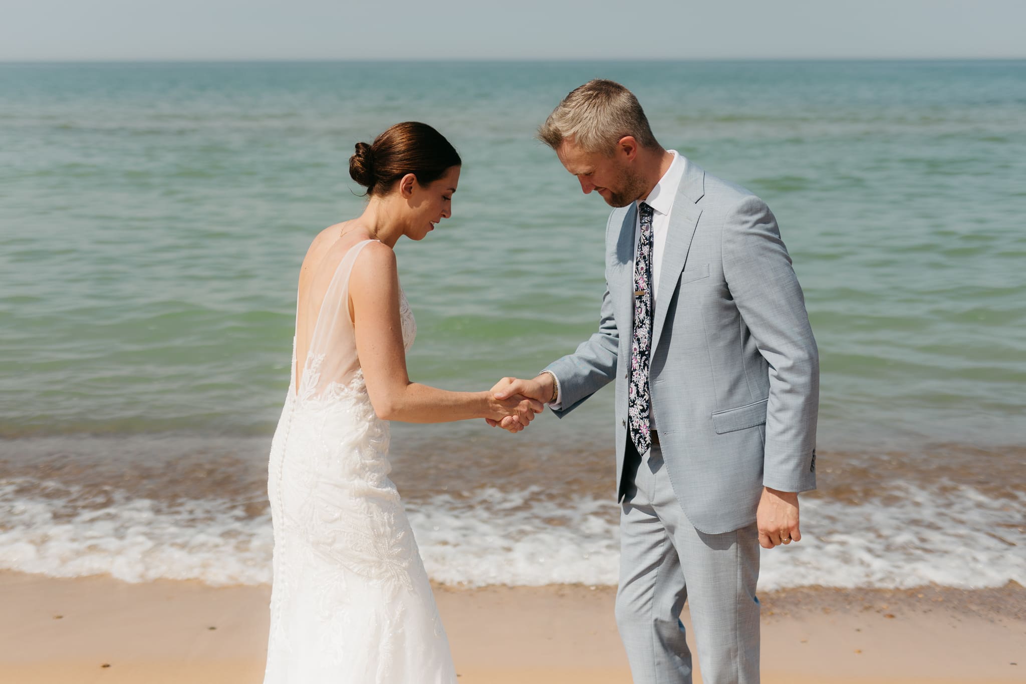 Bride and groom running along the shore of Lake Michigan during their elopement at Warren Dunes State Park