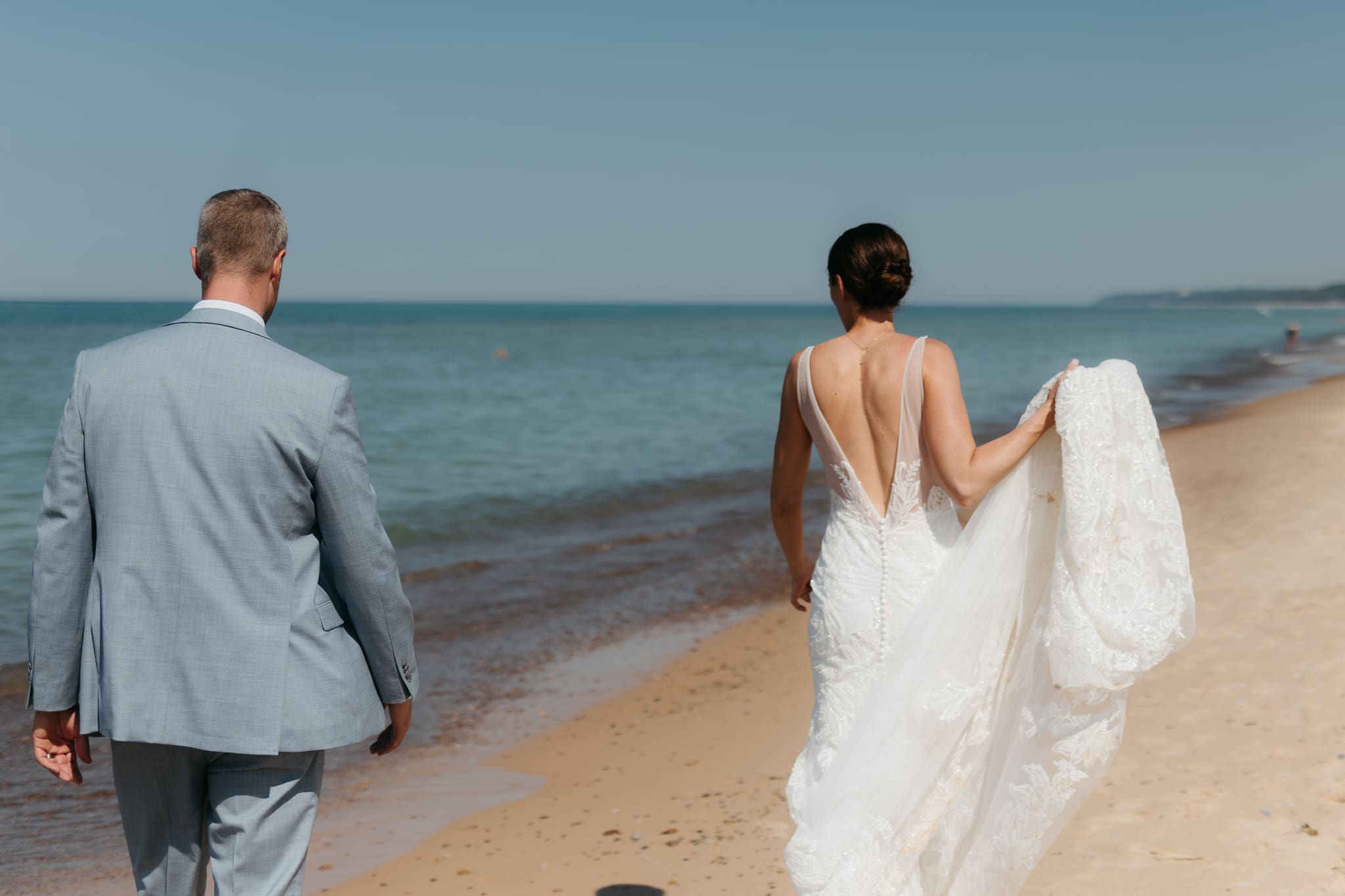 Bride and groom running along the shore of Lake Michigan during their elopement at Warren Dunes State Park