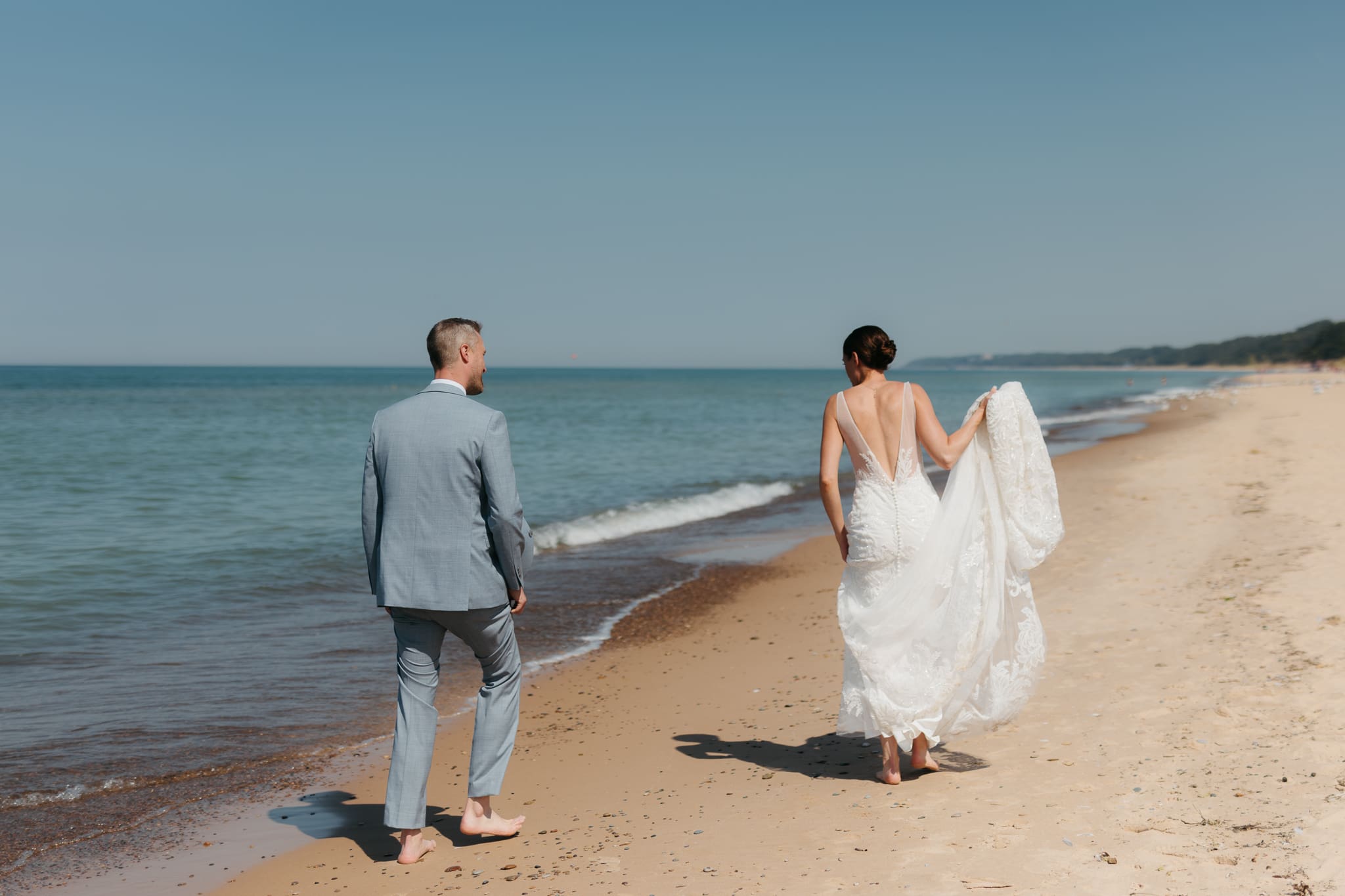 Bride and groom running along the shore of Lake Michigan during their elopement at Warren Dunes State Park