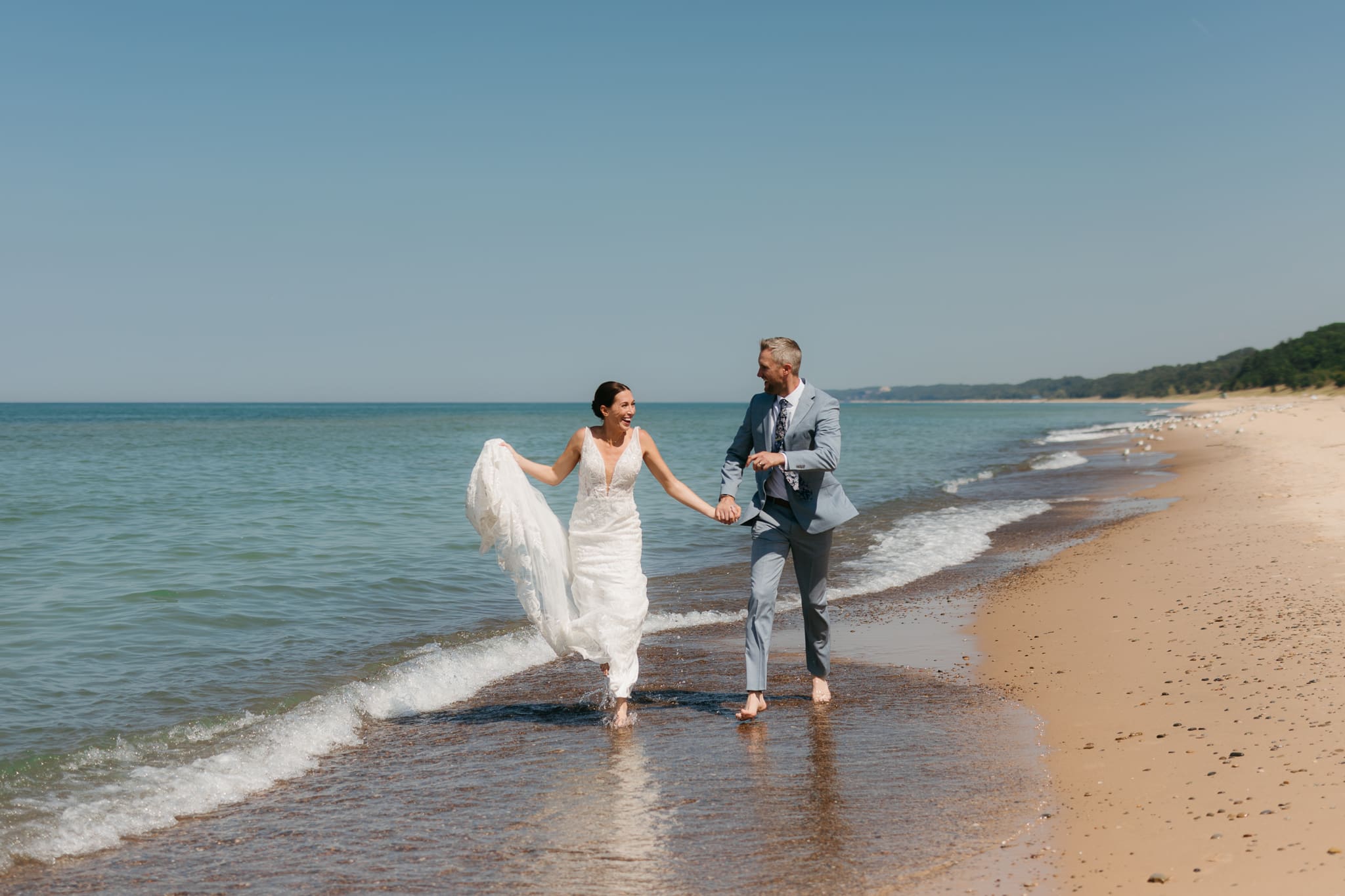 Bride and groom running along the shore of Lake Michigan during their elopement at Warren Dunes State Park