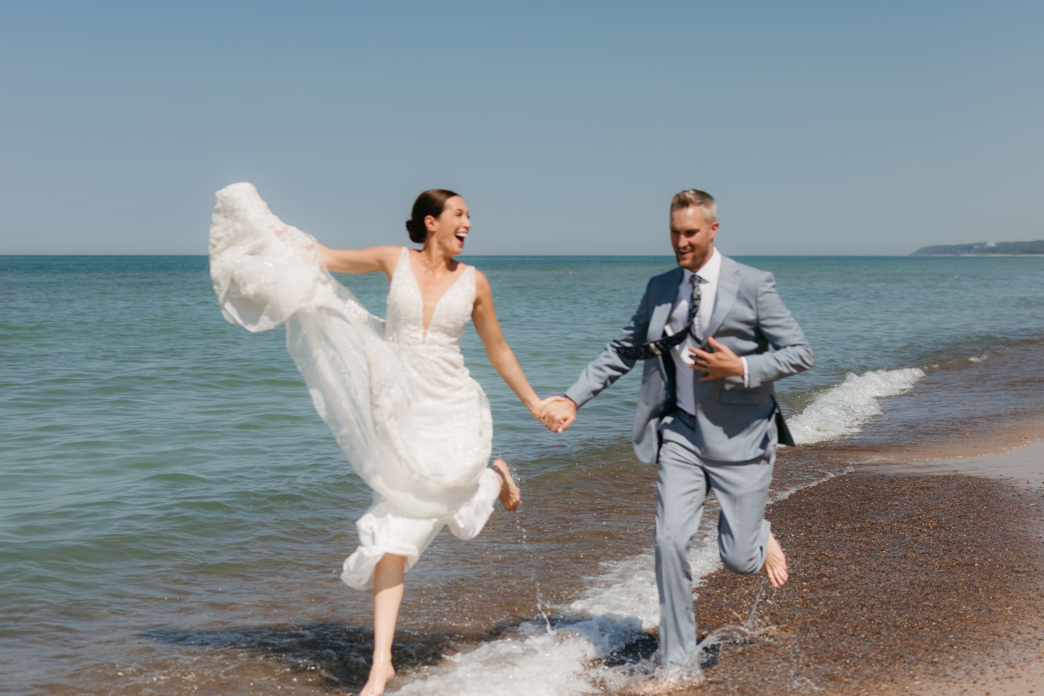 Bride and groom running along the shore of Lake Michigan during their elopement at Warren Dunes State Park