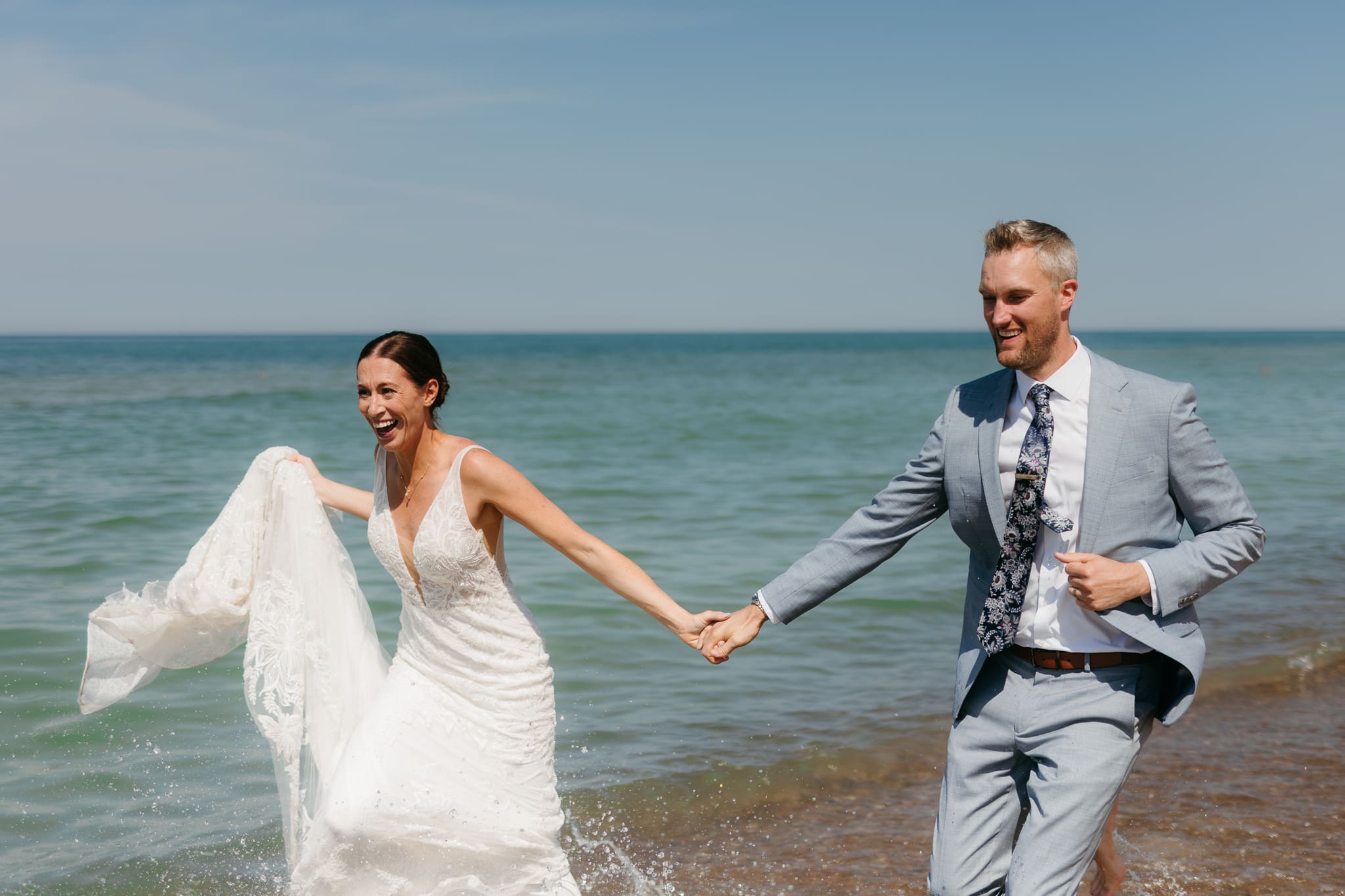 Bride and groom running along the shore of Lake Michigan during their elopement at Warren Dunes State Park