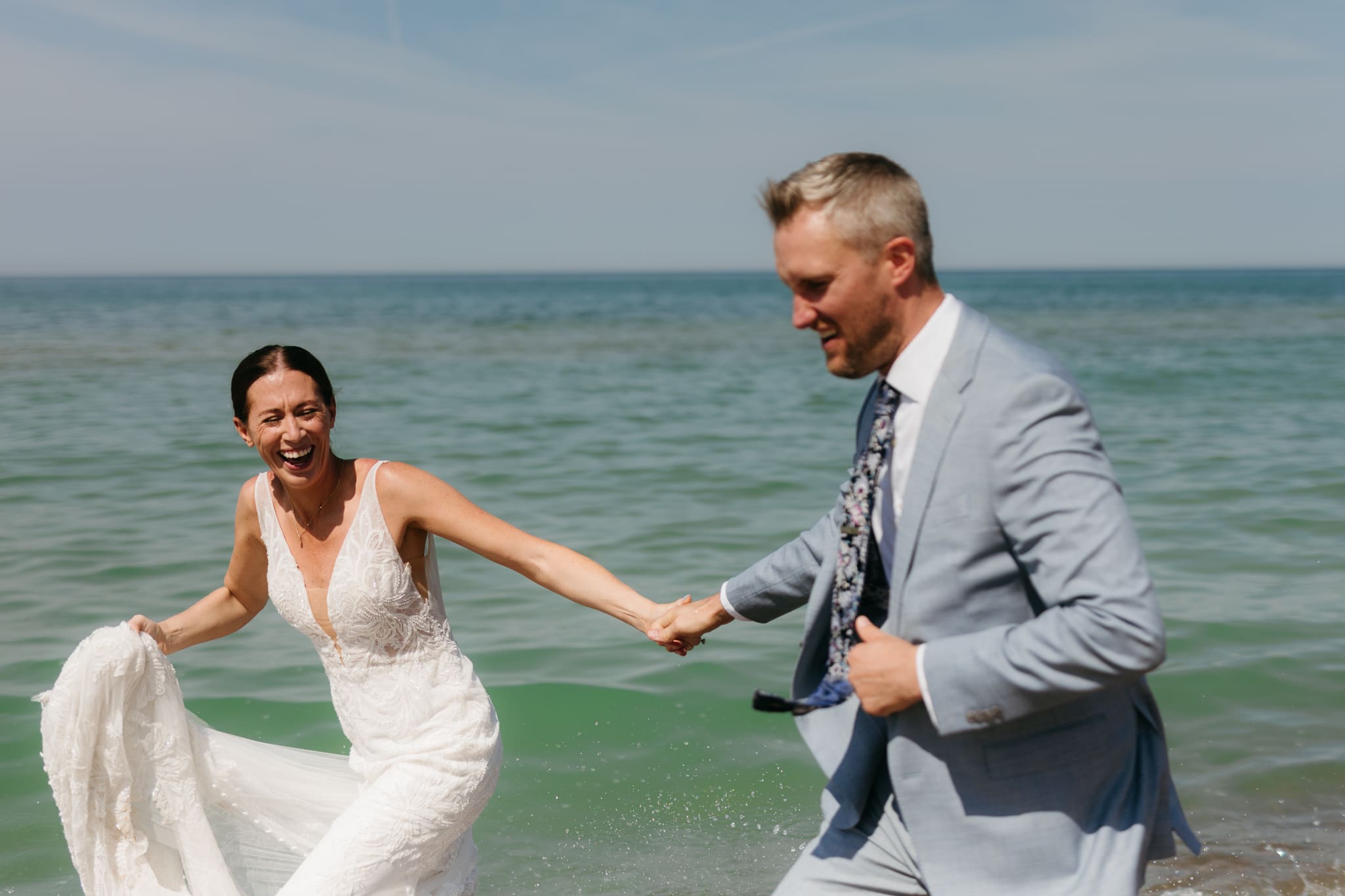 Bride and groom running along the shore of Lake Michigan during their elopement at Warren Dunes State Park