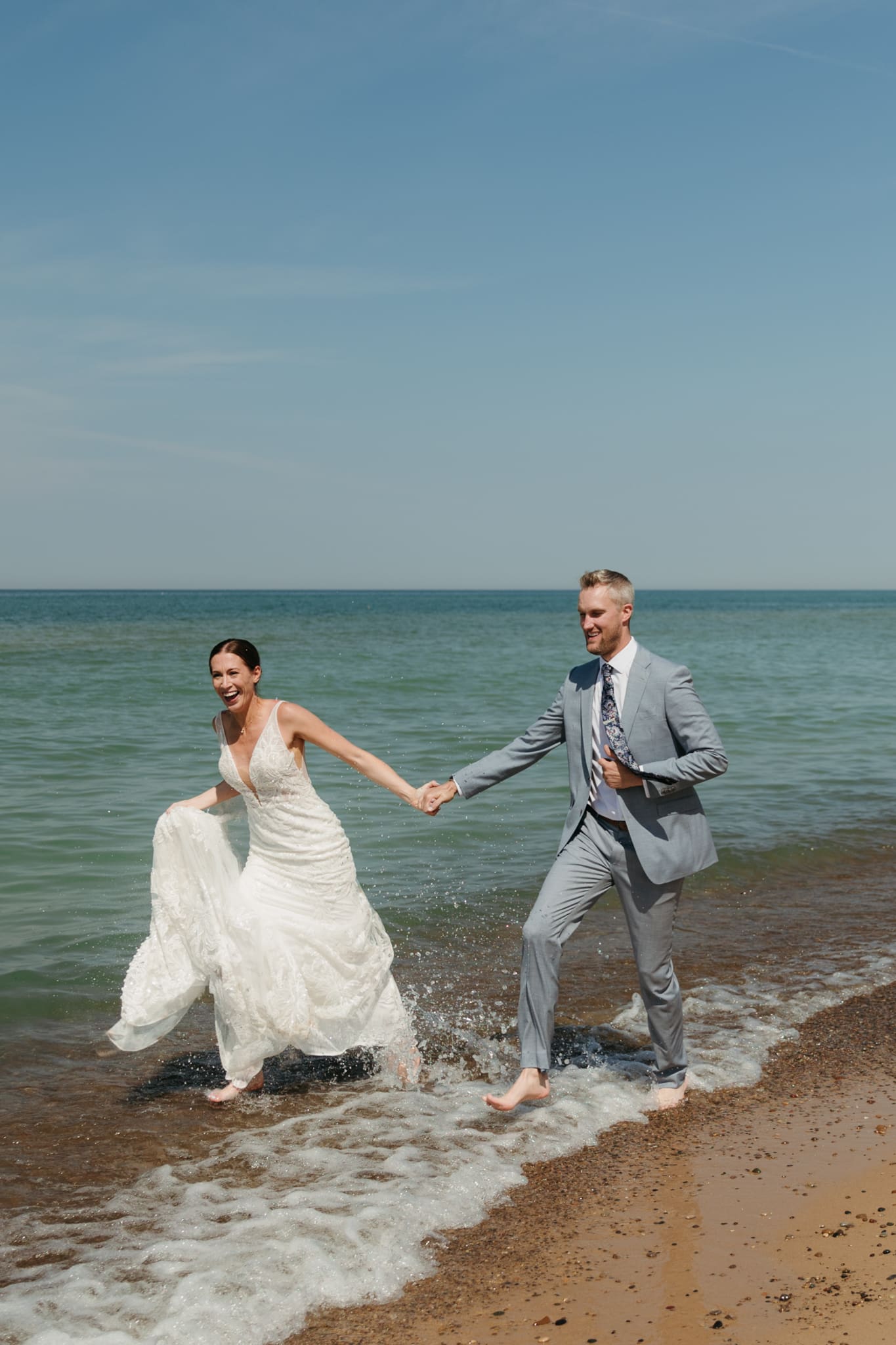 Bride and groom running along the shore of Lake Michigan during their elopement at Warren Dunes State Park