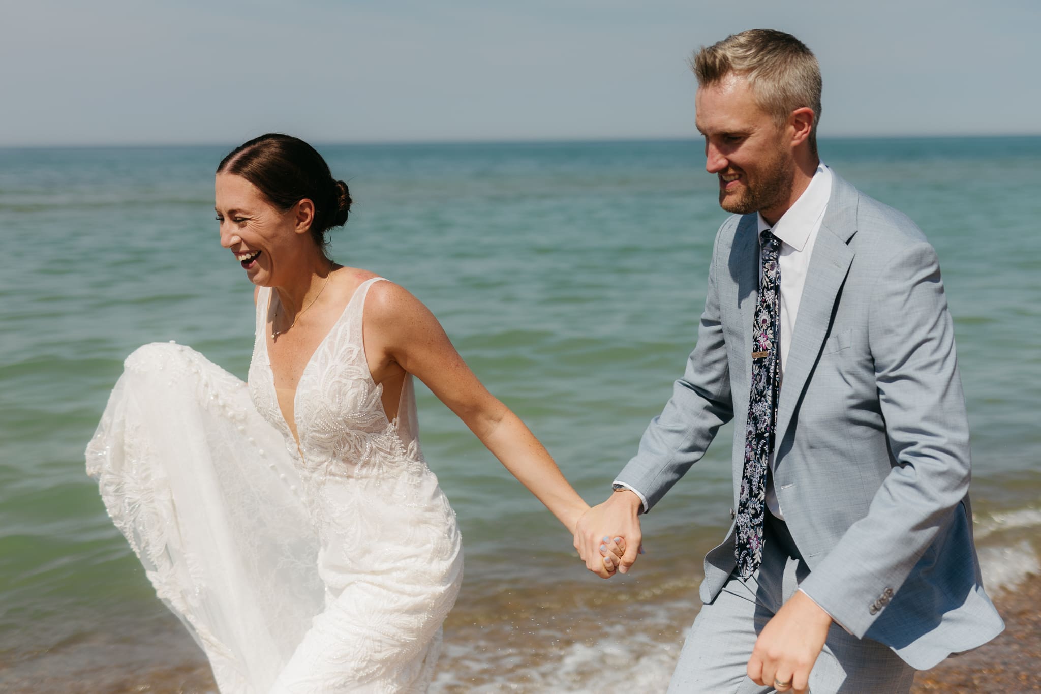Bride and groom running along the shore of Lake Michigan during their elopement at Warren Dunes State Park