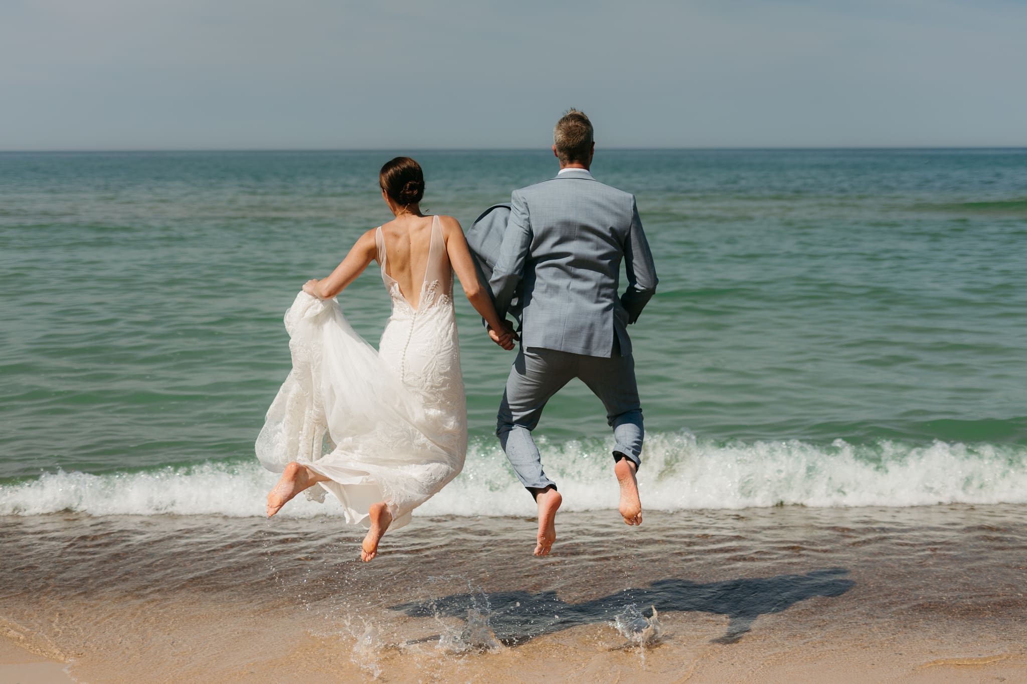 Bride and groom running along the shore of Lake Michigan during their elopement at Warren Dunes State Park