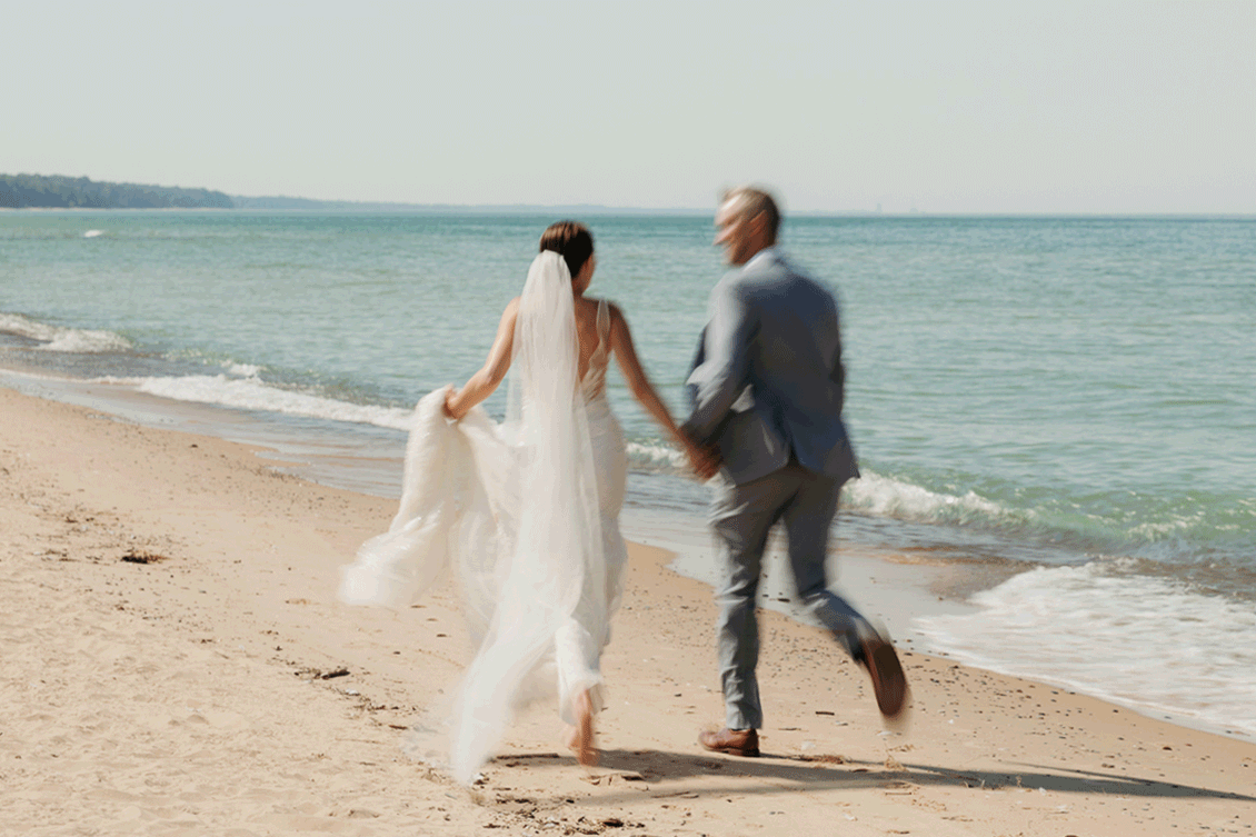 Bride and groom embracing and enjoying their Warren Dunes State Park elopement while running along the beach