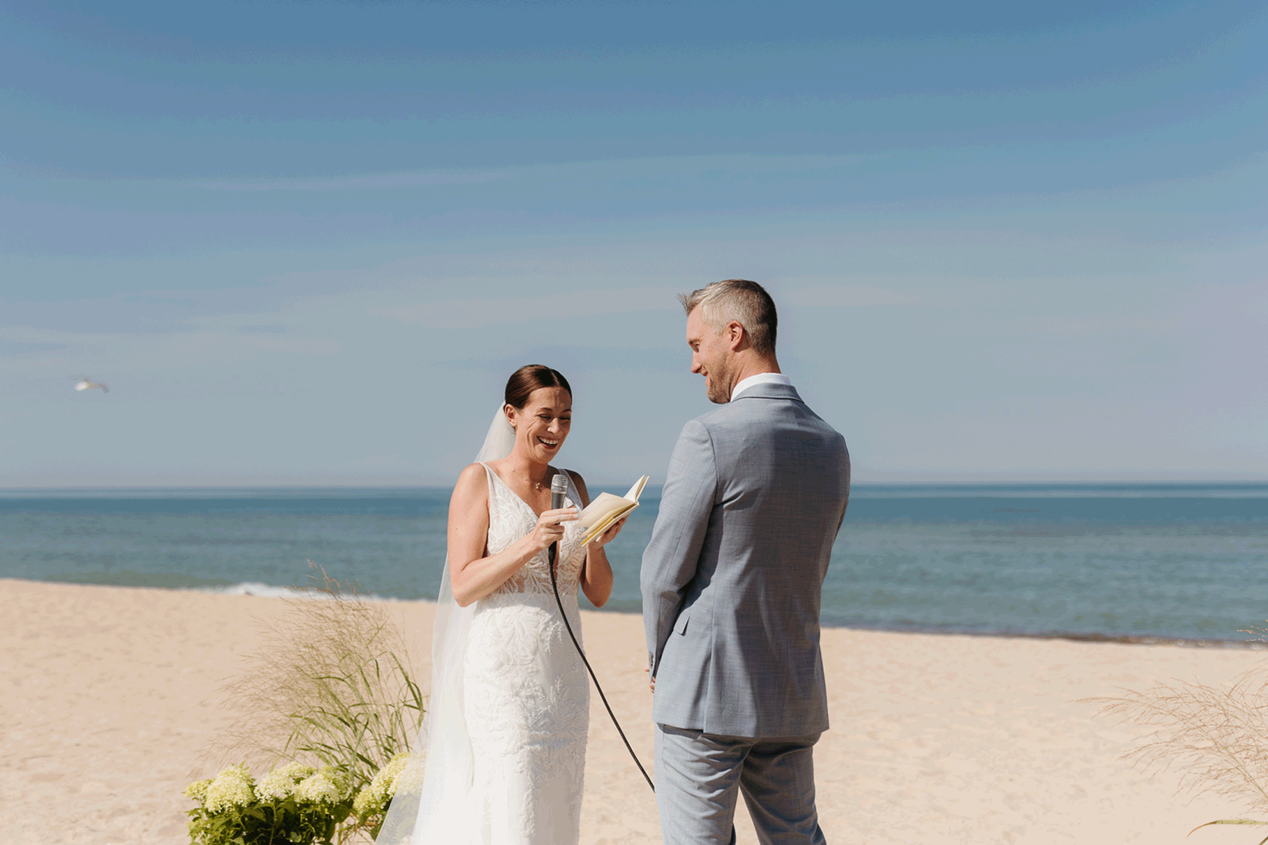 Bride and groom exchange vows on the beach during their Lake Michigan wedding ceremony at Warren Dunes State Park
