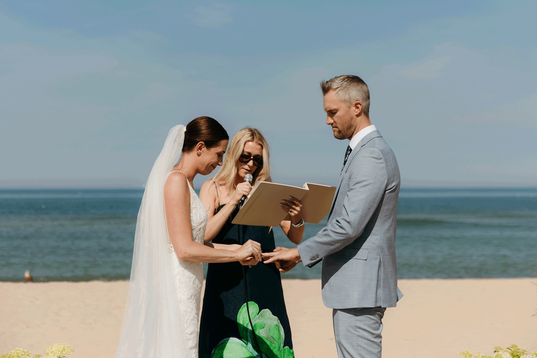Bride and groom exchange vows and rings on the beach during their Lake Michigan wedding ceremony at Warren Dunes State Park