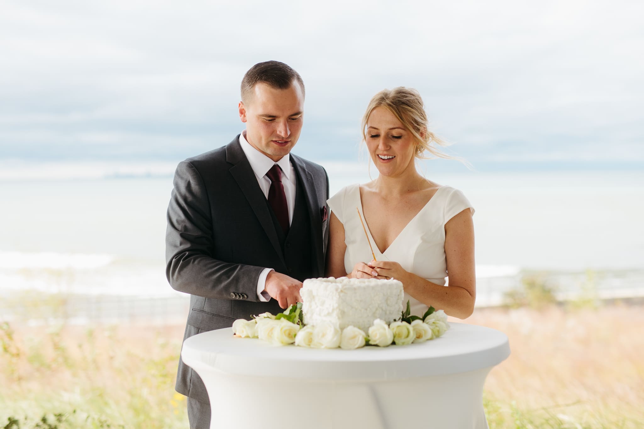 Bride and groom cut cake during their outdoor wedding reception at Indiana Dunes National Park