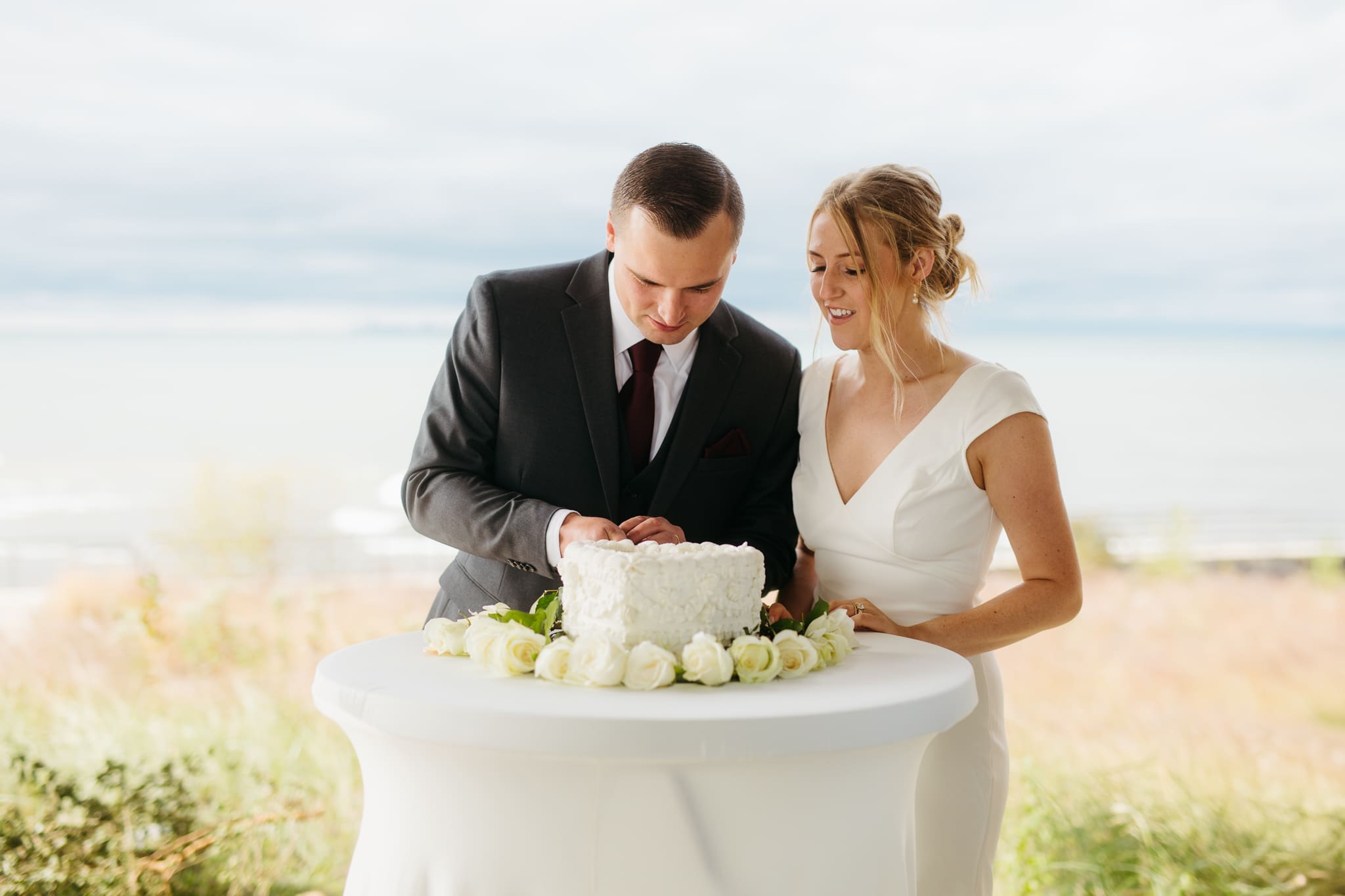 Bride and groom cut cake during their outdoor wedding reception at Indiana Dunes National Park