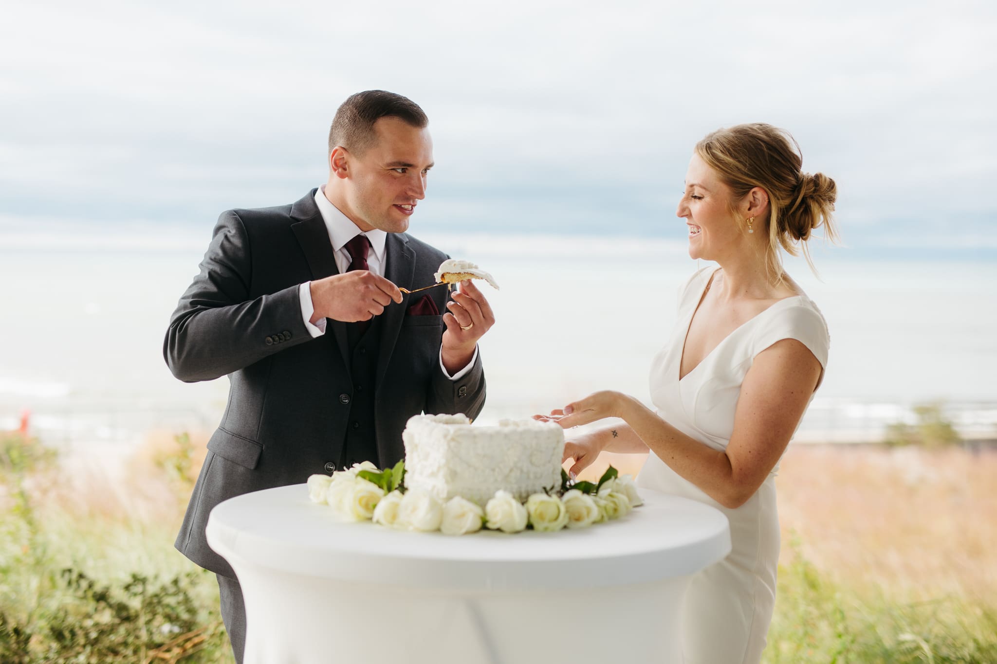 Bride and groom cut cake during their outdoor wedding reception at Indiana Dunes National Park