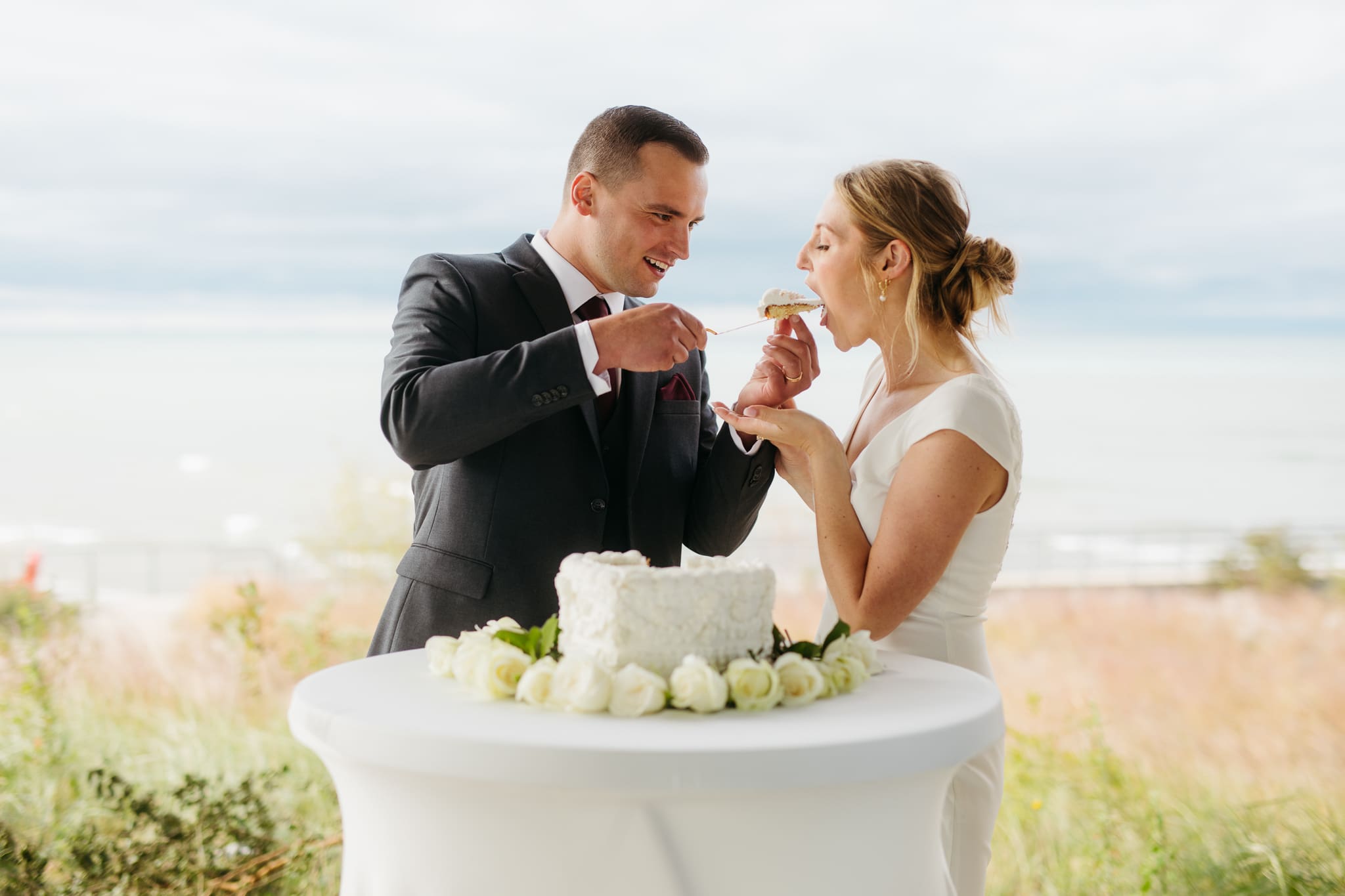 Bride and groom cut cake during their outdoor wedding reception at Indiana Dunes National Park