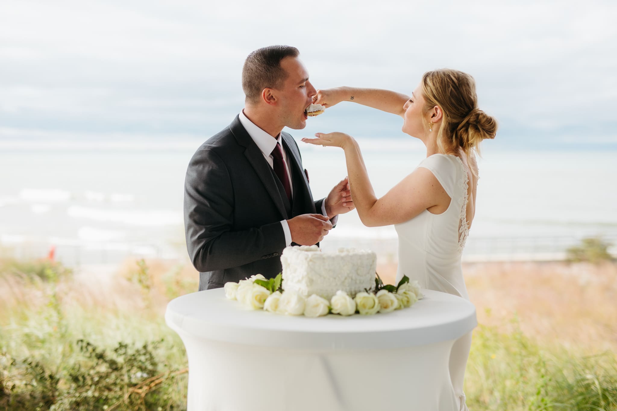 Bride and groom cut cake during their outdoor wedding reception at Indiana Dunes National Park