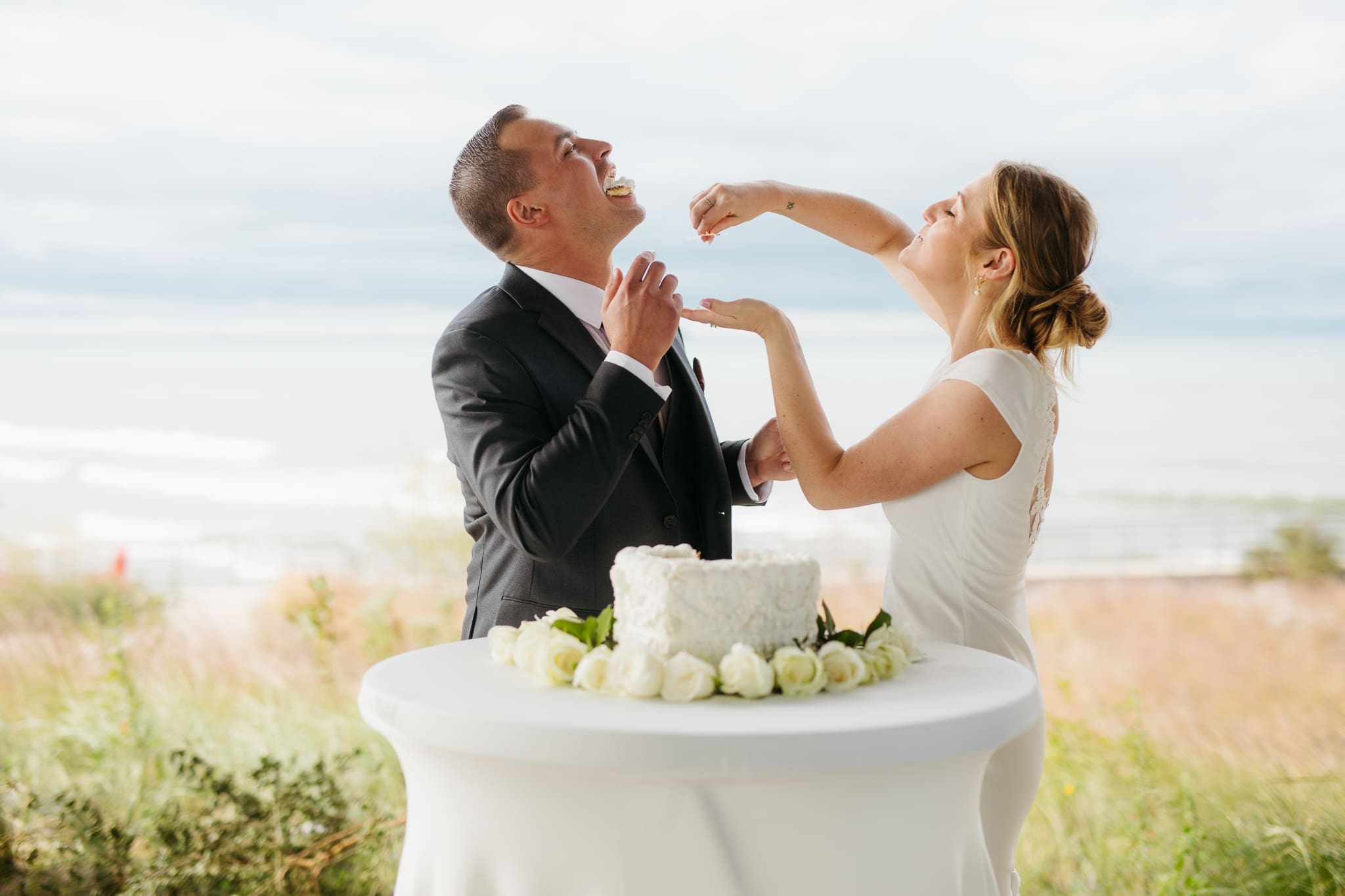 Bride and groom cut cake during their outdoor wedding reception at Indiana Dunes National Park