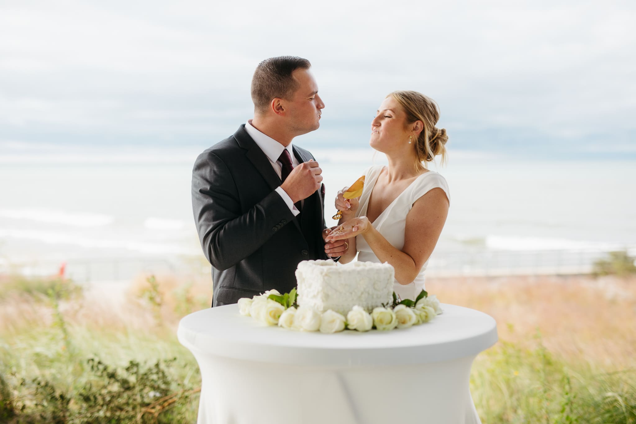 Bride and groom cut cake during their outdoor wedding reception at Indiana Dunes National Park
