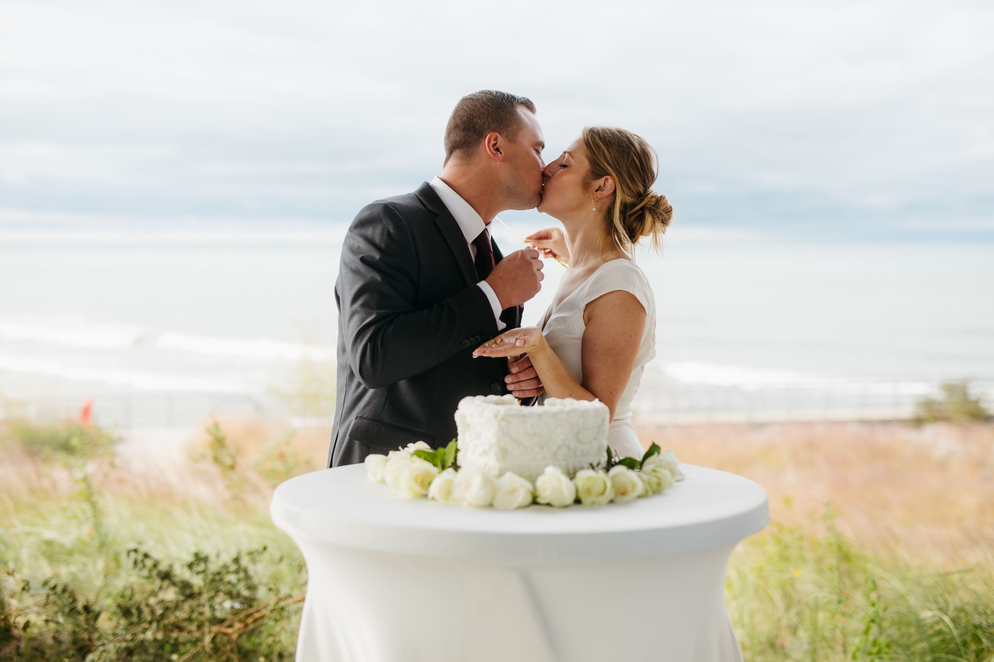 Bride and groom cut cake during their outdoor wedding reception at Indiana Dunes National Park