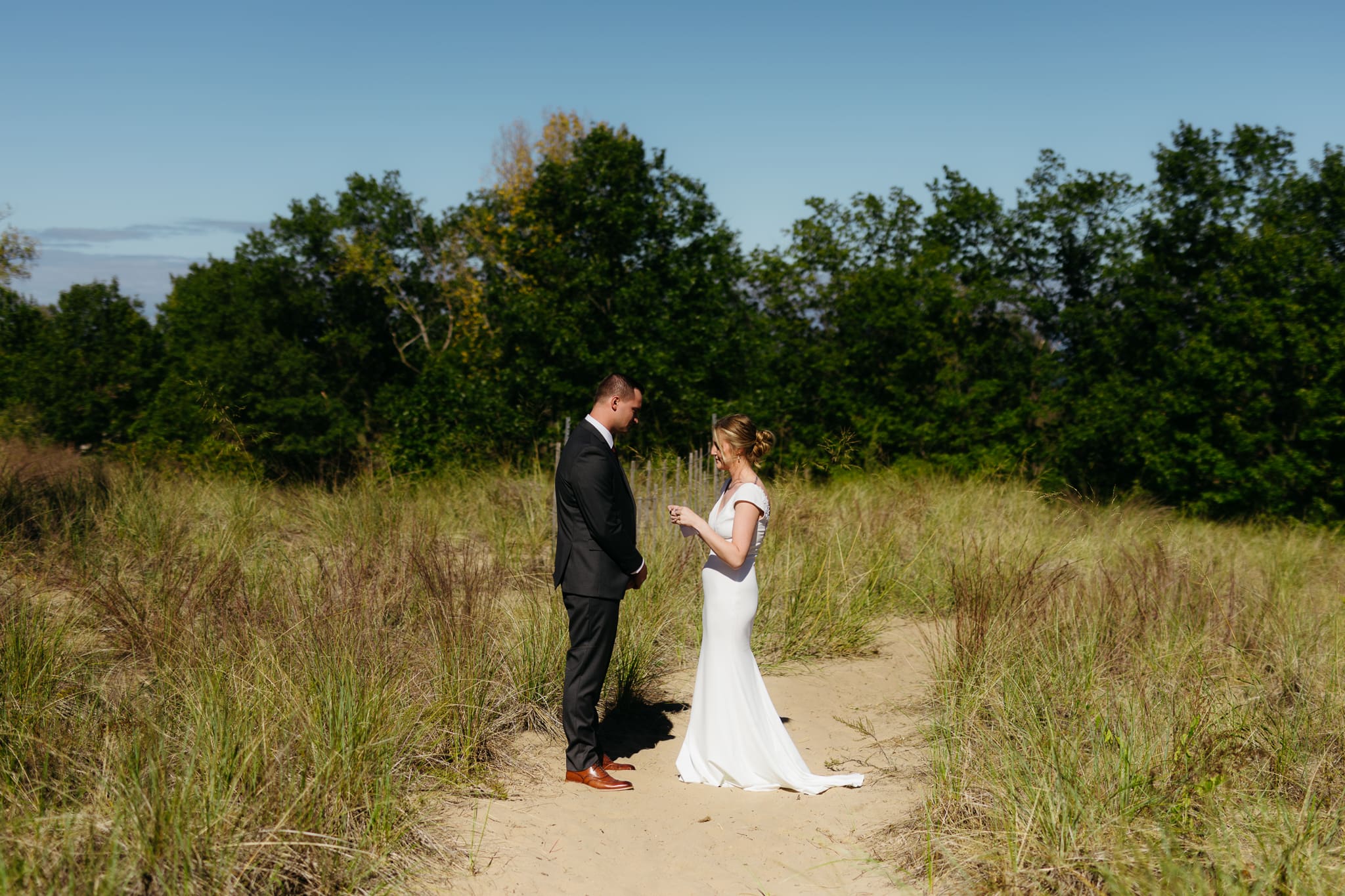 Bride and groom exchange private vows among the dunes of Indiana Dunes National Park, with dune grass swaying in the breeze.