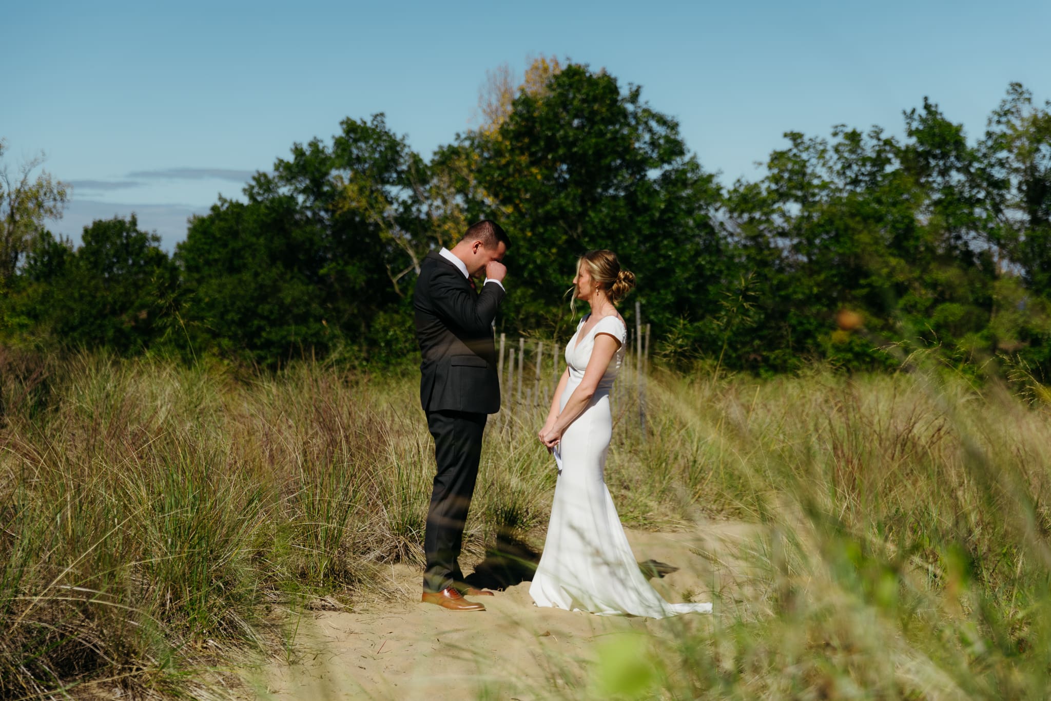 Bride and groom exchange private vows among the dunes of Indiana Dunes National Park, with dune grass swaying in the breeze.