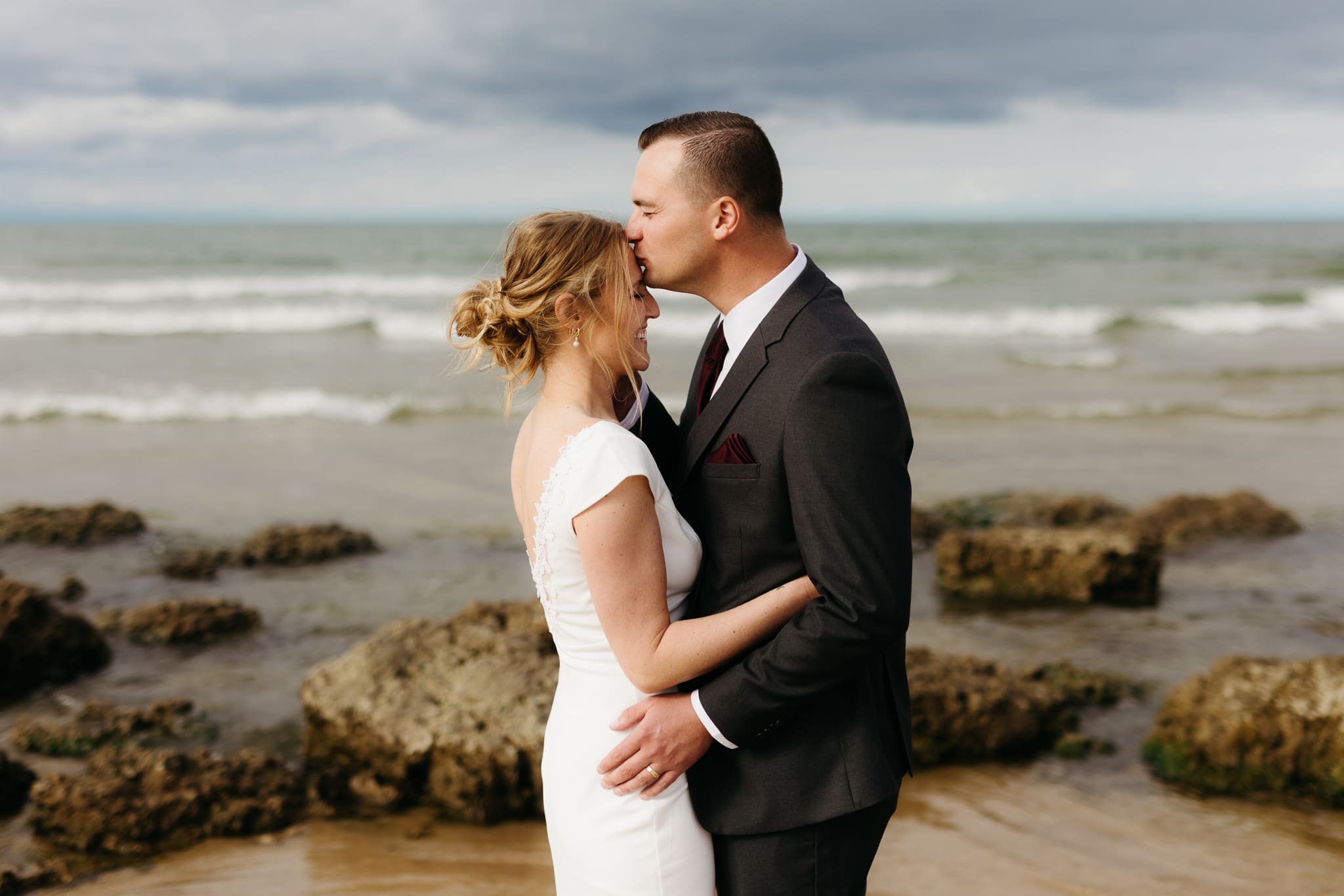 Bride and groom embrace and take couple portraits together along the beach of Lake Michigan during their Indiana Dunes National Park wedding.