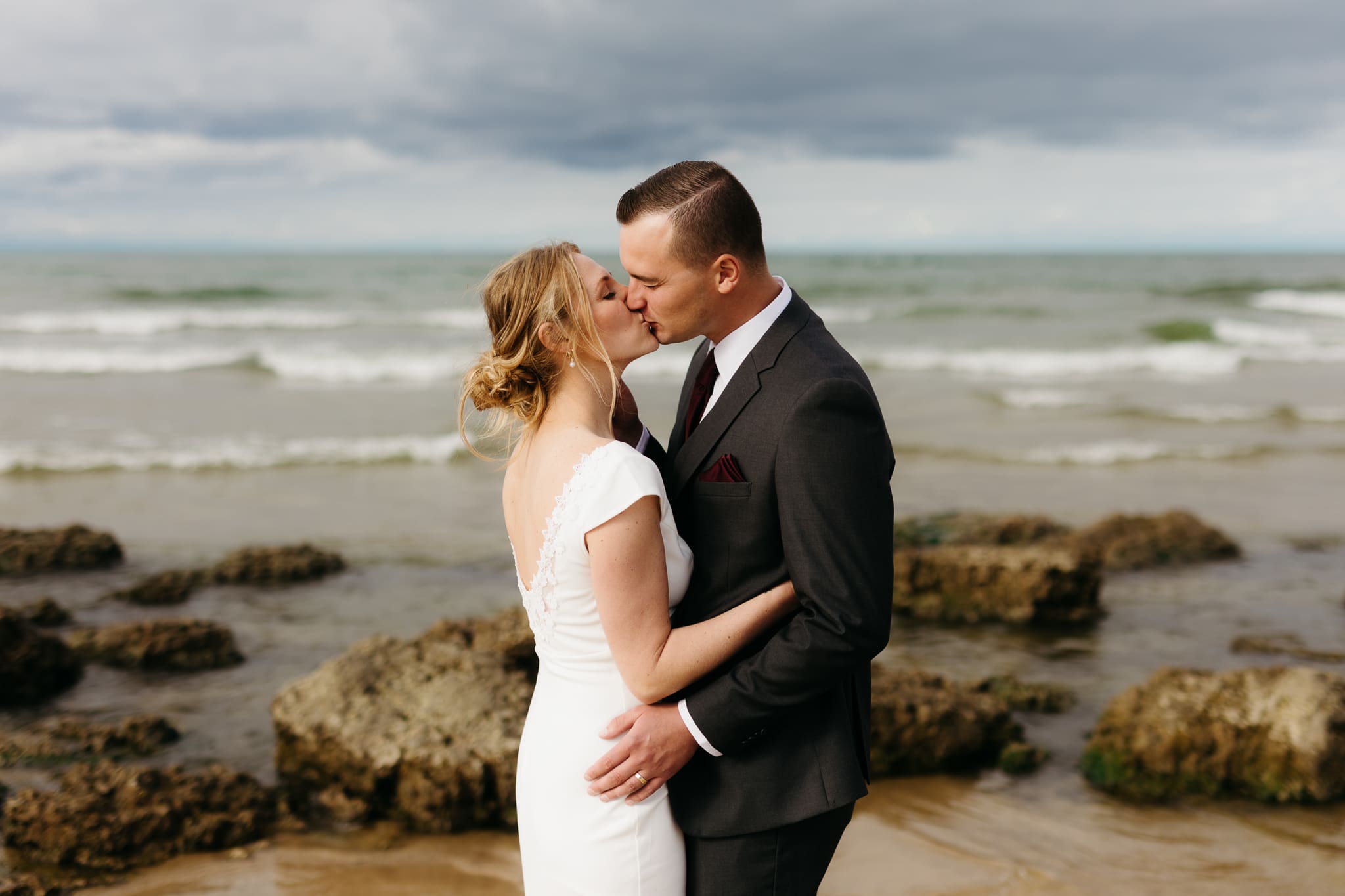 Bride and groom embrace and take couple portraits together along the beach of Lake Michigan during their Indiana Dunes National Park wedding.