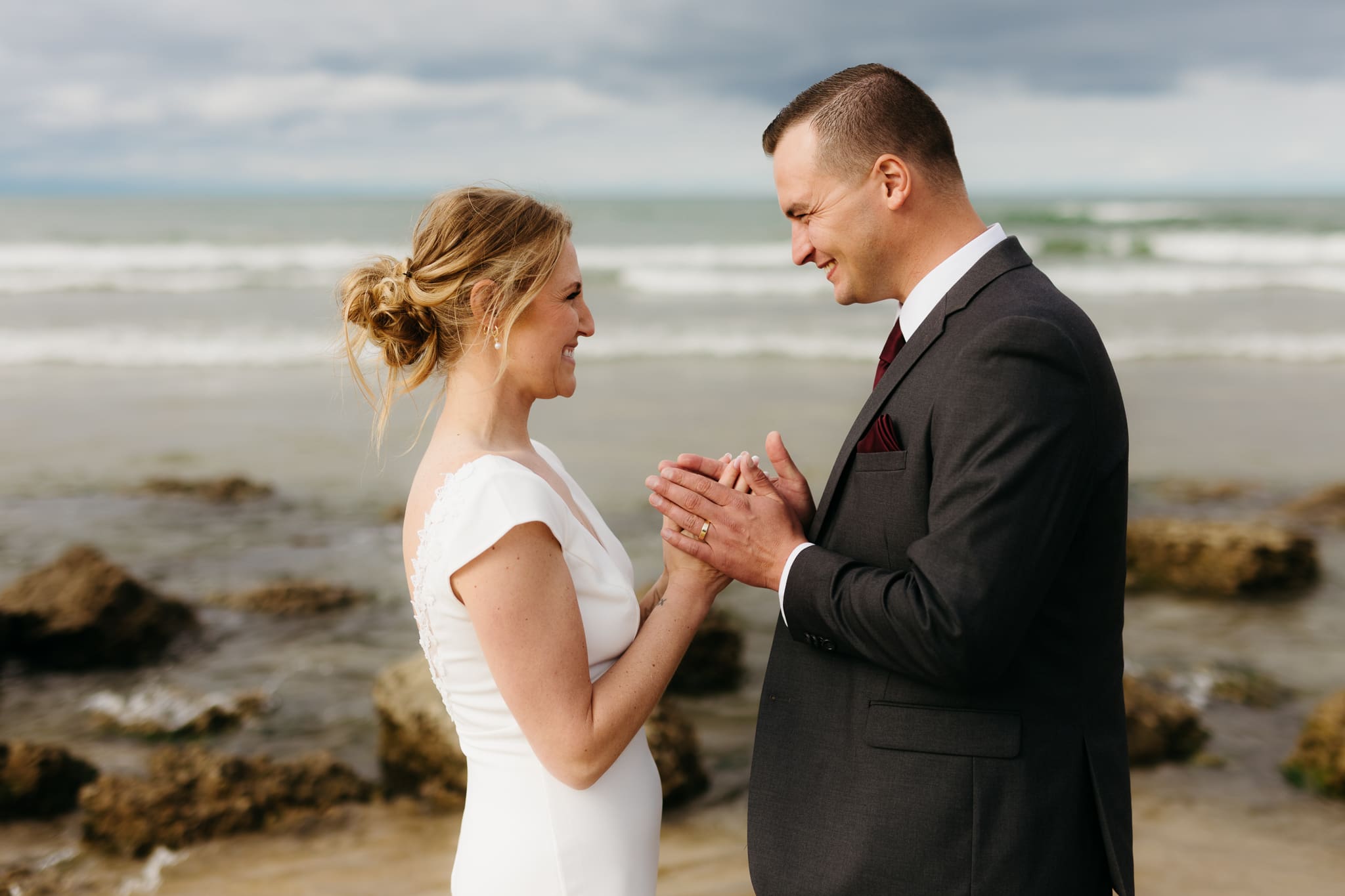 Bride and groom embrace and take couple portraits together along the beach of Lake Michigan during their Indiana Dunes National Park wedding.