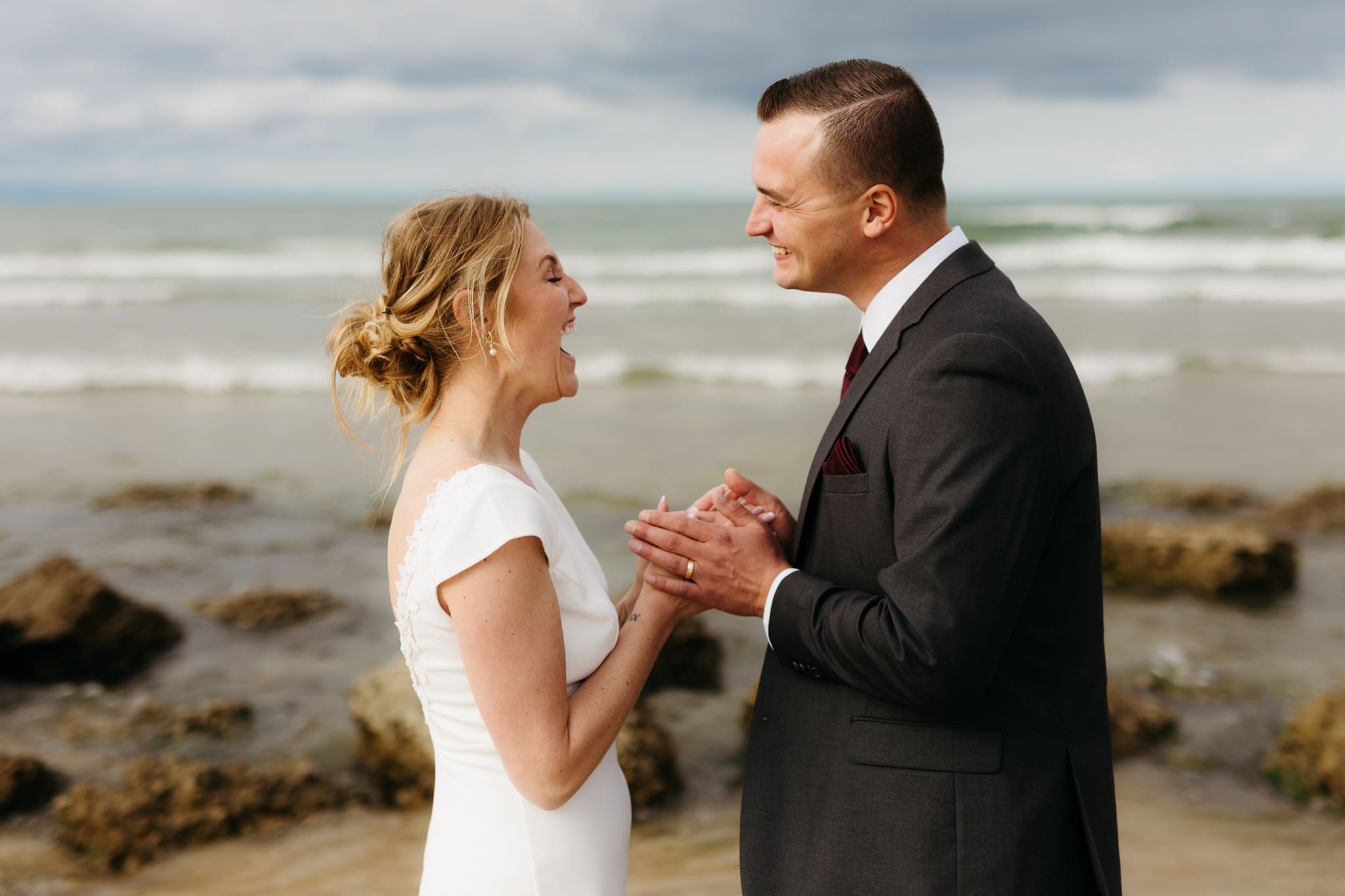 Bride and groom embrace and take couple portraits together along the beach of Lake Michigan during their Indiana Dunes National Park wedding.