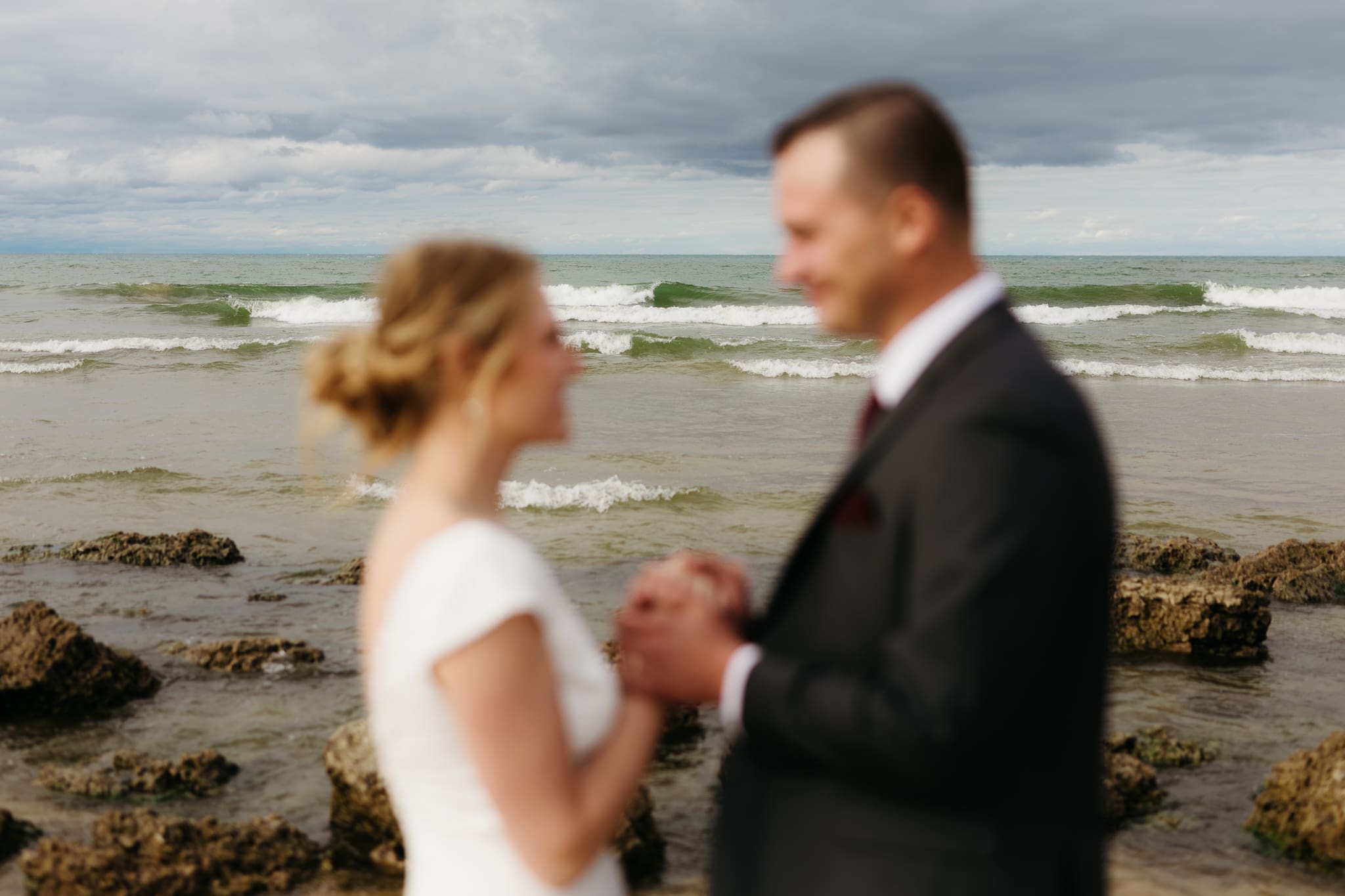 Bride and groom embrace and take couple portraits together along the beach of Lake Michigan during their Indiana Dunes National Park wedding.