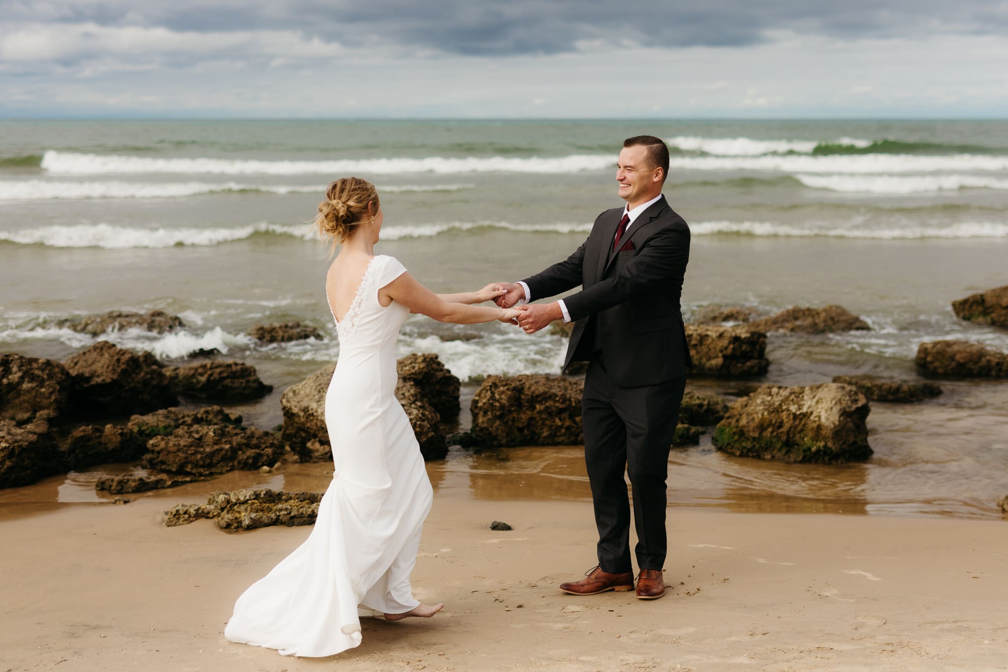 Bride and groom embrace and take couple portraits together along the beach of Lake Michigan during their Indiana Dunes National Park wedding.
