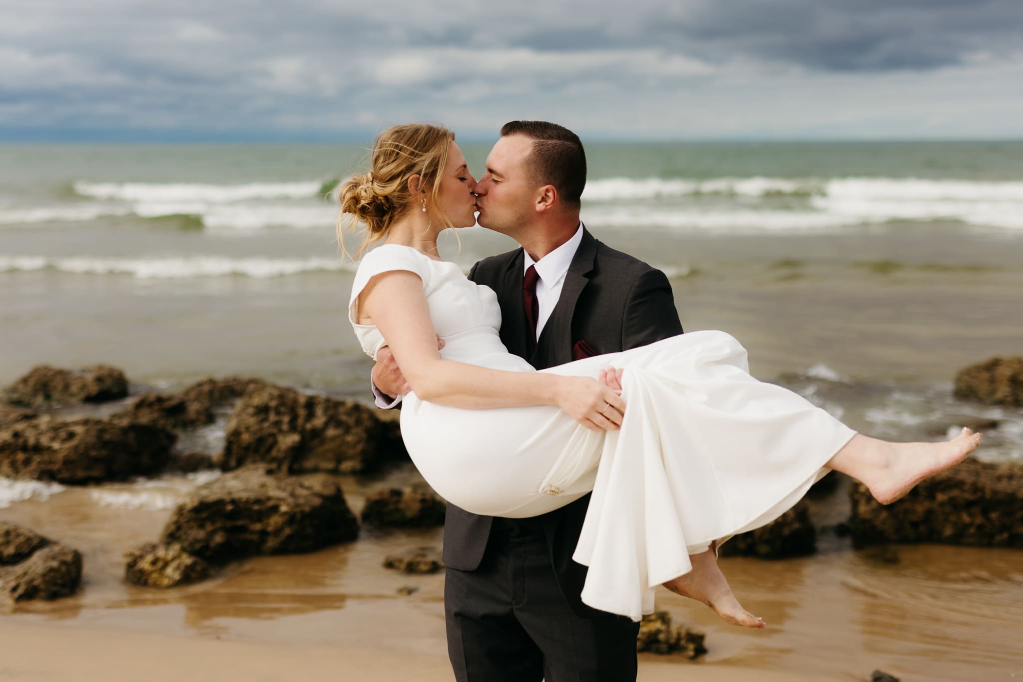 Bride and groom embrace and take couple portraits together along the beach of Lake Michigan during their Indiana Dunes National Park wedding.