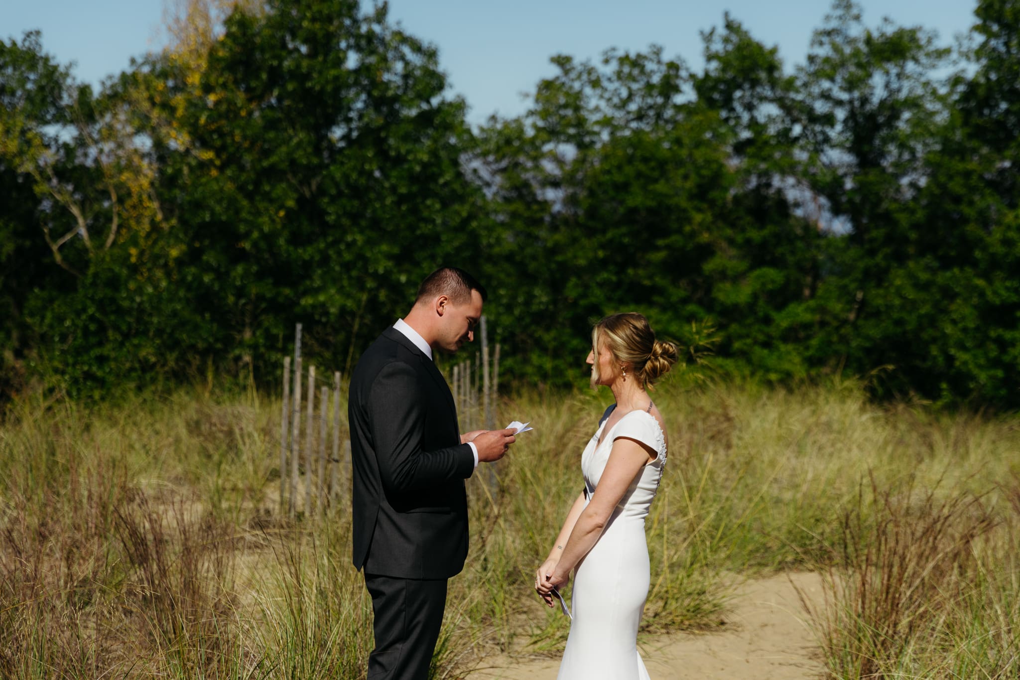 Bride and groom exchange private vows among the dunes of Indiana Dunes National Park, with dune grass swaying in the breeze.