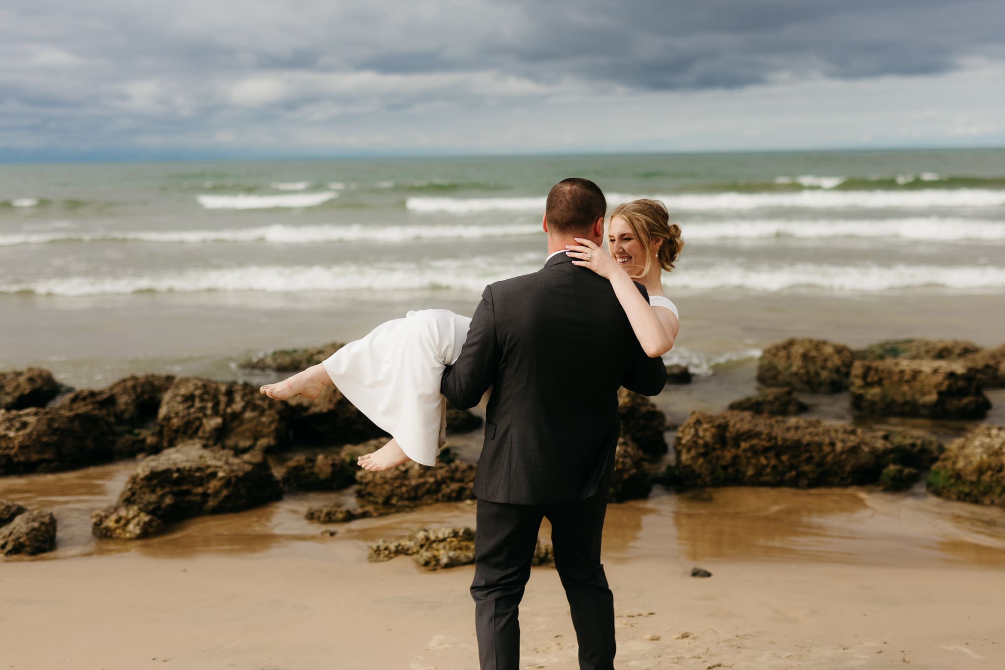 Bride and groom embrace and take couple portraits together along the beach of Lake Michigan during their Indiana Dunes National Park wedding.