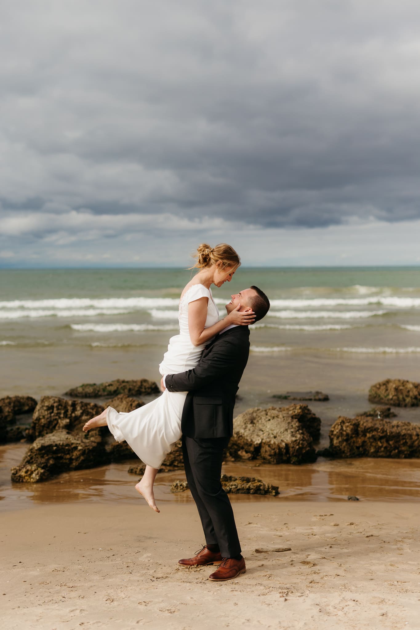 Bride and groom embrace and take couple portraits together along the beach of Lake Michigan during their Indiana Dunes National Park wedding.
