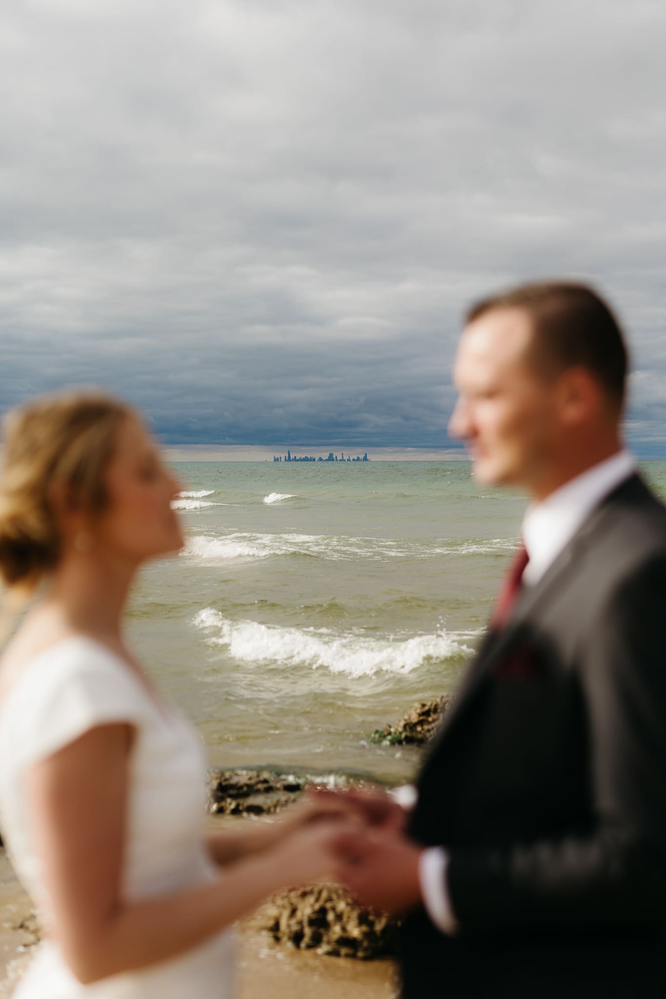 Bride and groom embrace and take couple portraits together along the beach of Lake Michigan during their Indiana Dunes National Park wedding.