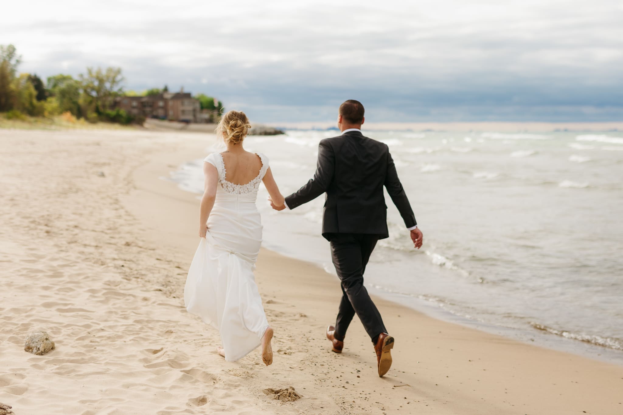Bride and groom embrace and take couple portraits together along the beach of Lake Michigan during their Indiana Dunes National Park wedding.