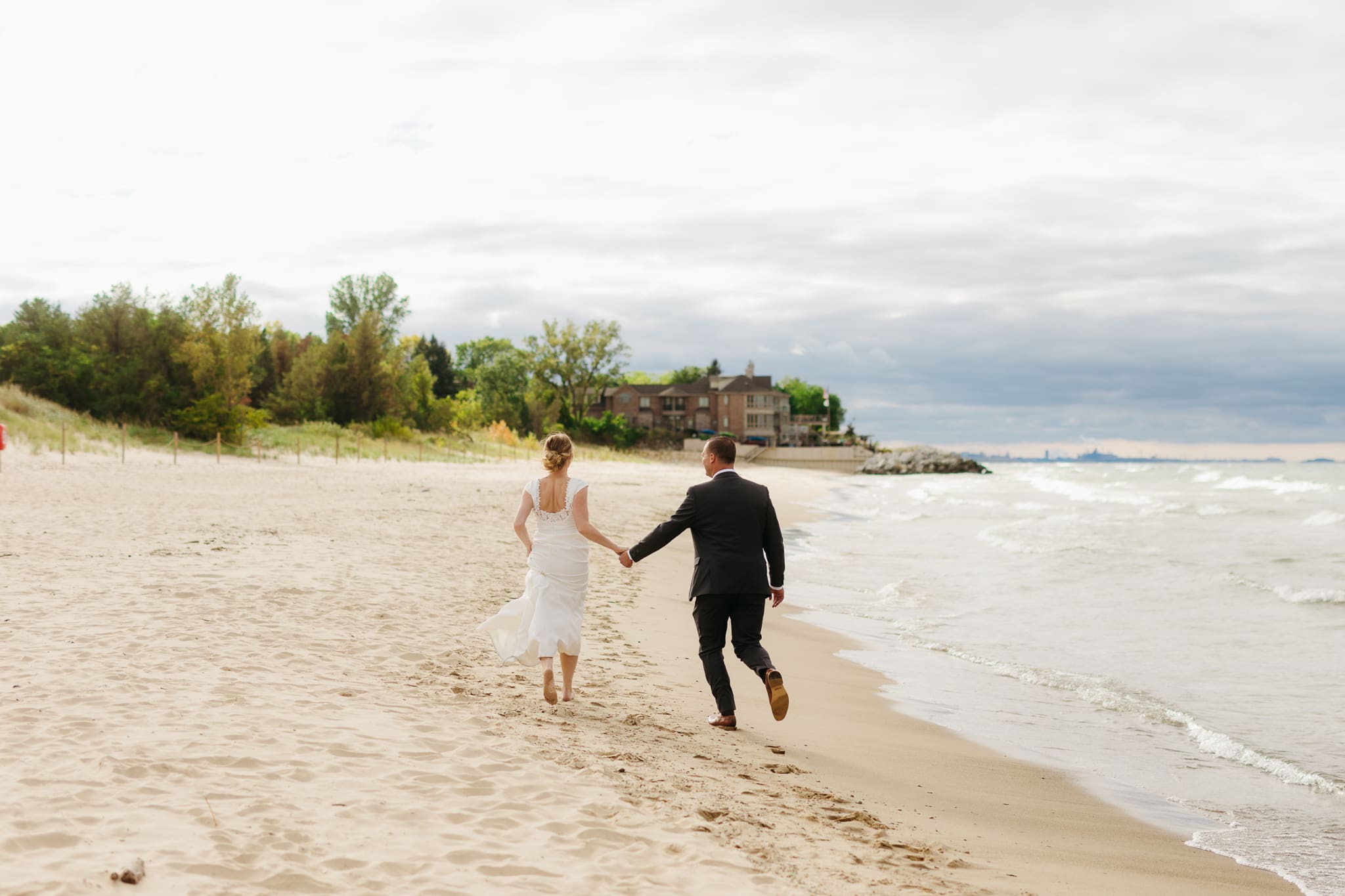 Bride and groom embrace and take couple portraits together along the beach of Lake Michigan during their Indiana Dunes National Park wedding.