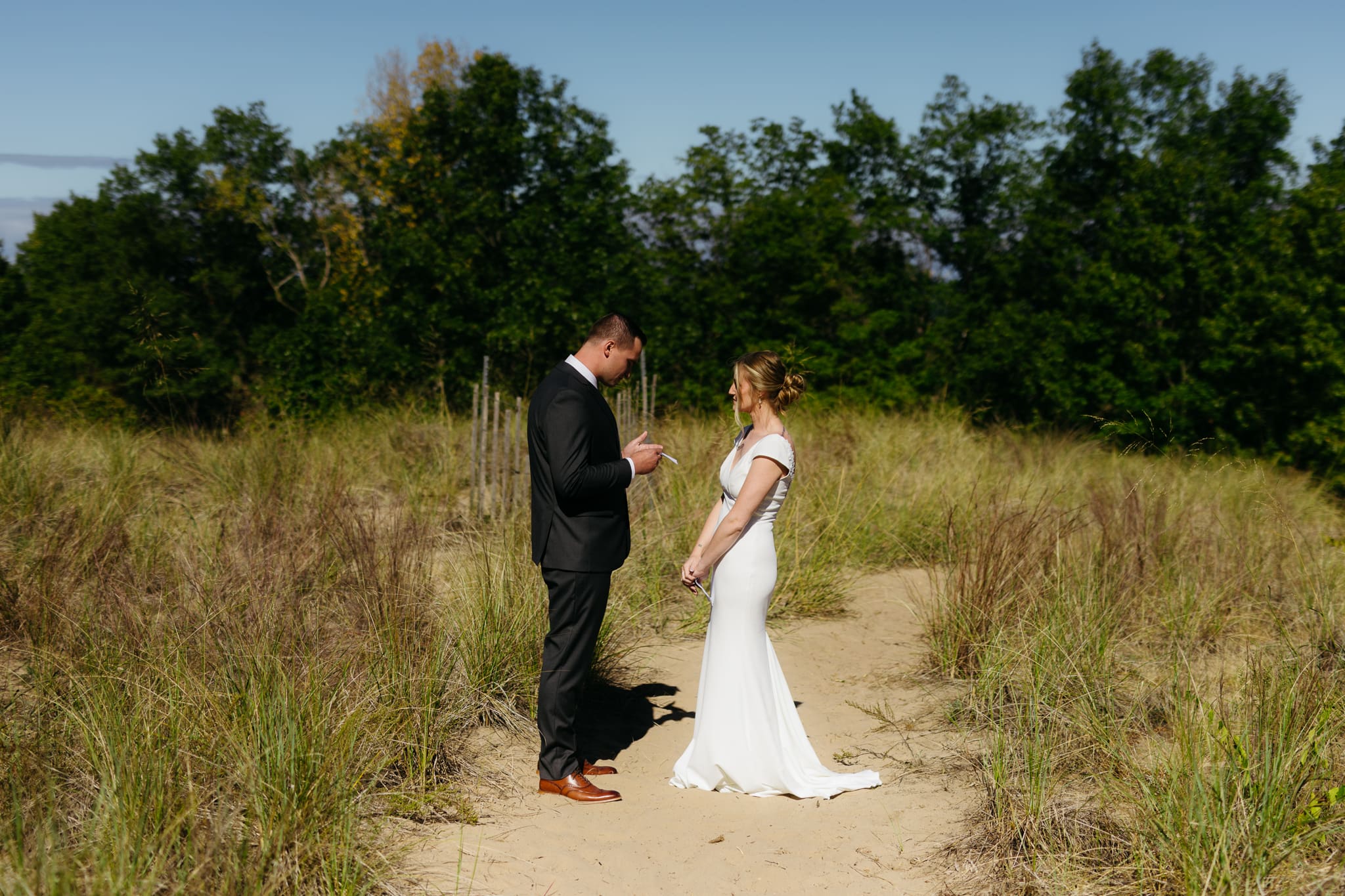 Bride and groom exchange private vows among the dunes of Indiana Dunes National Park, with dune grass swaying in the breeze.