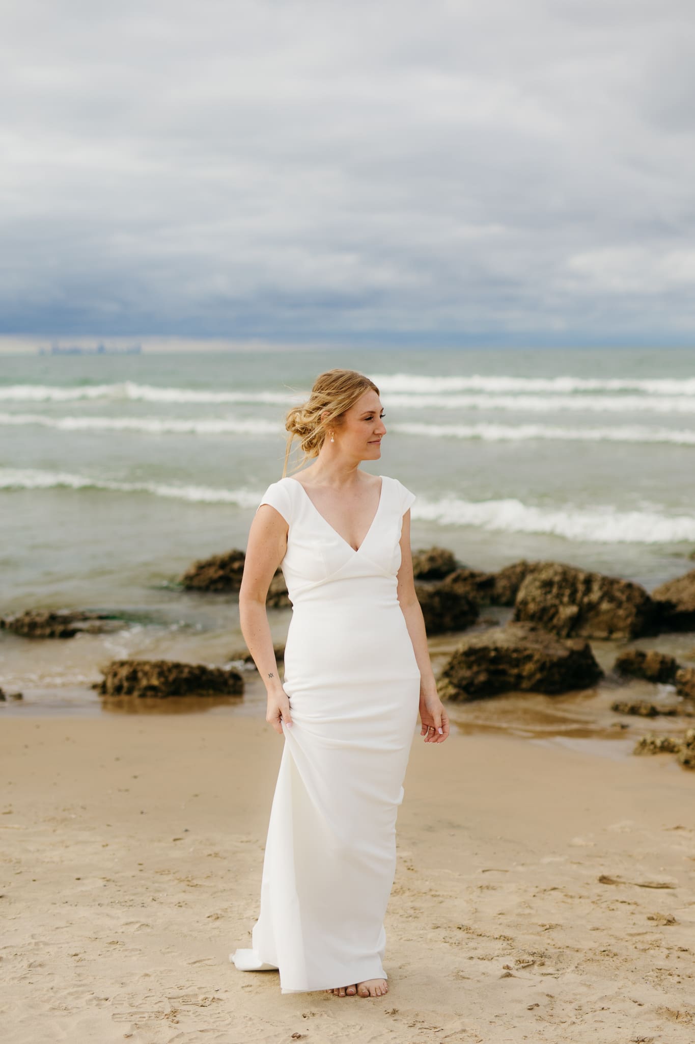 Bride and groom embrace and take couple portraits together along the beach of Lake Michigan during their Indiana Dunes National Park wedding.