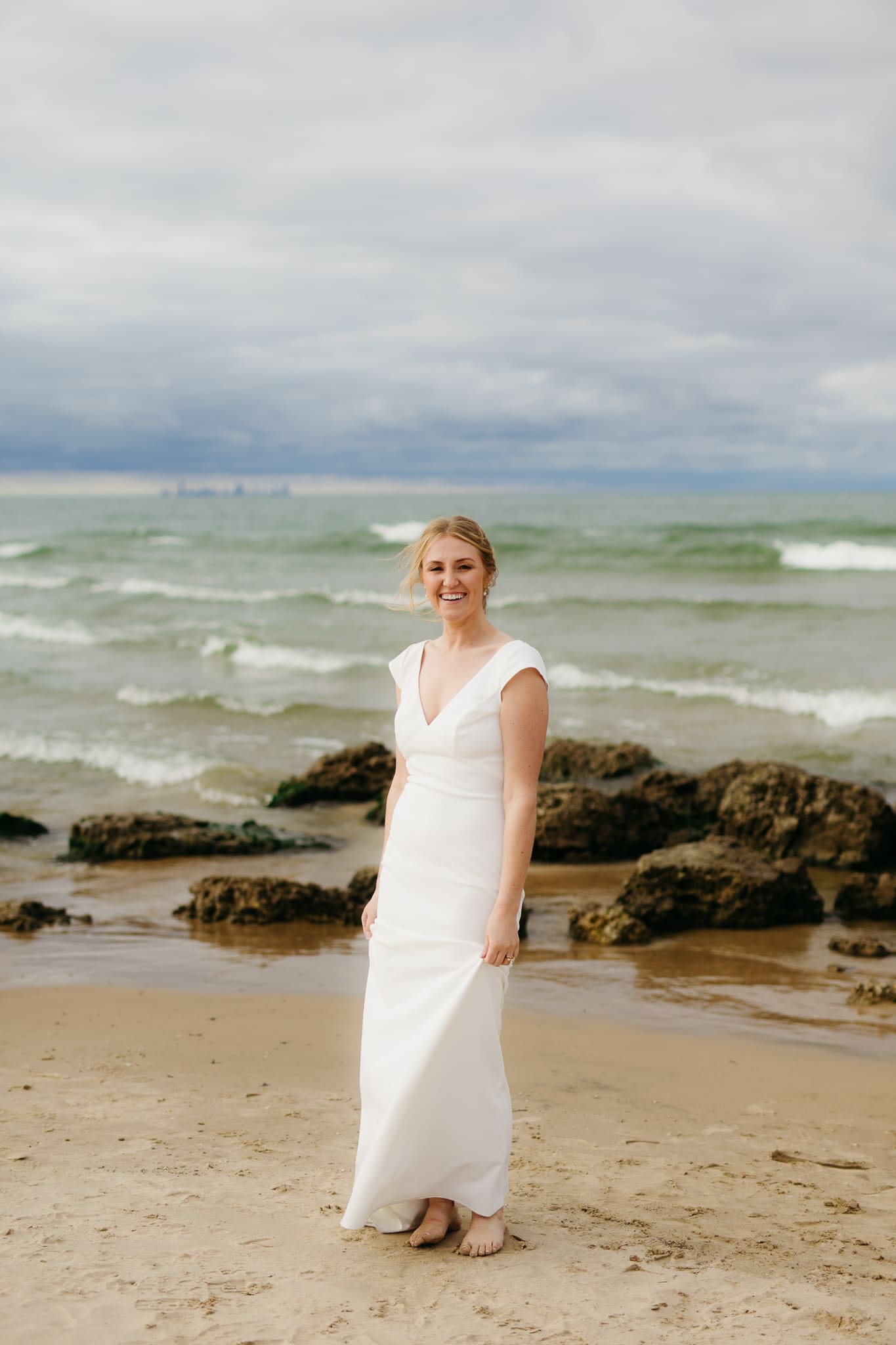 Bride and groom embrace and take couple portraits together along the beach of Lake Michigan during their Indiana Dunes National Park wedding.