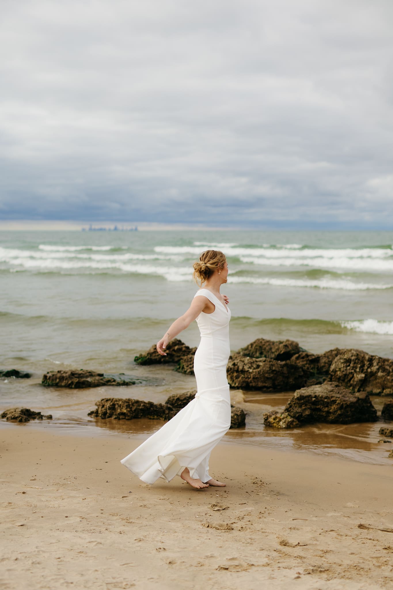 Bride and groom embrace and take couple portraits together along the beach of Lake Michigan during their Indiana Dunes National Park wedding.