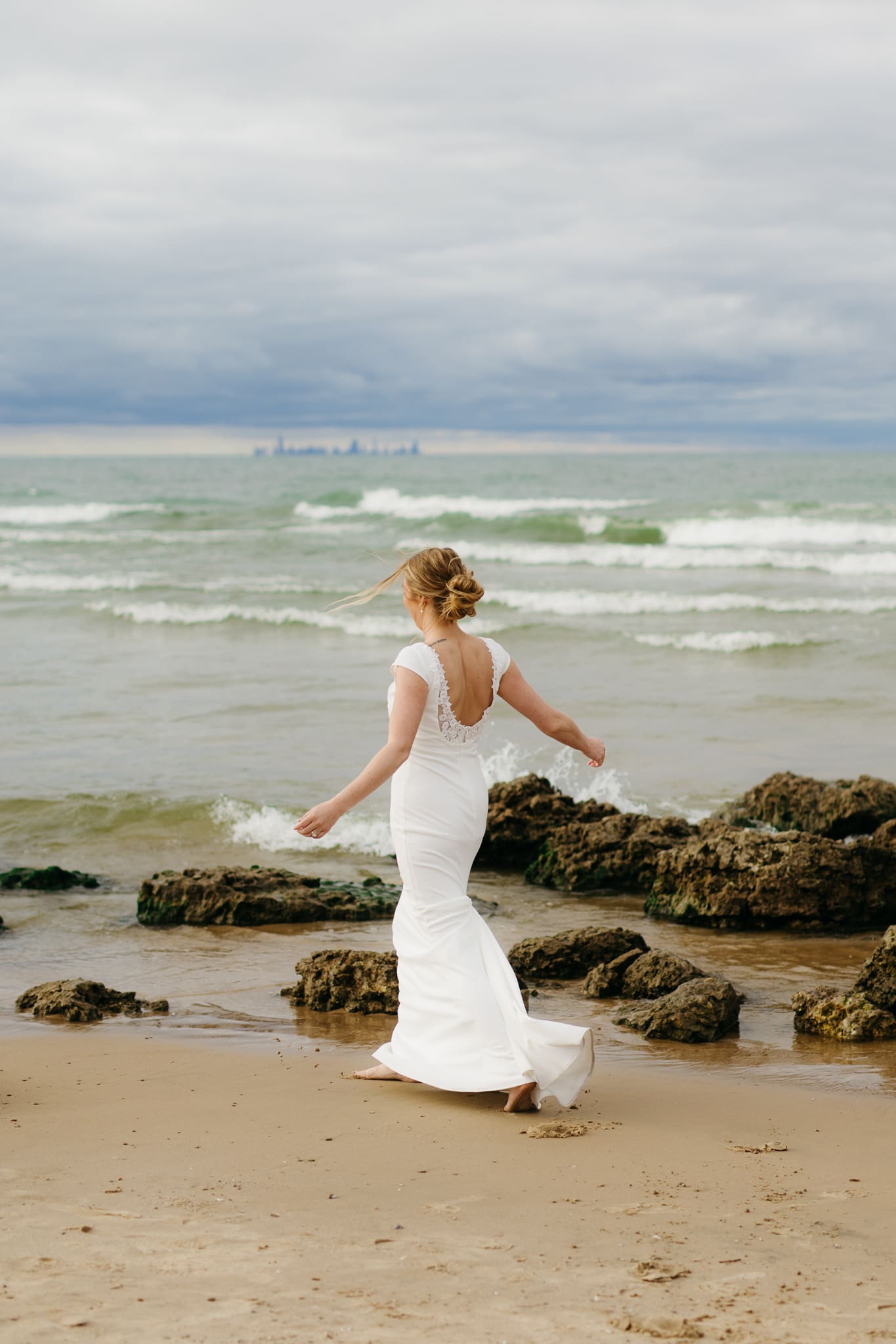 Bride and groom embrace and take couple portraits together along the beach of Lake Michigan during their Indiana Dunes National Park wedding.