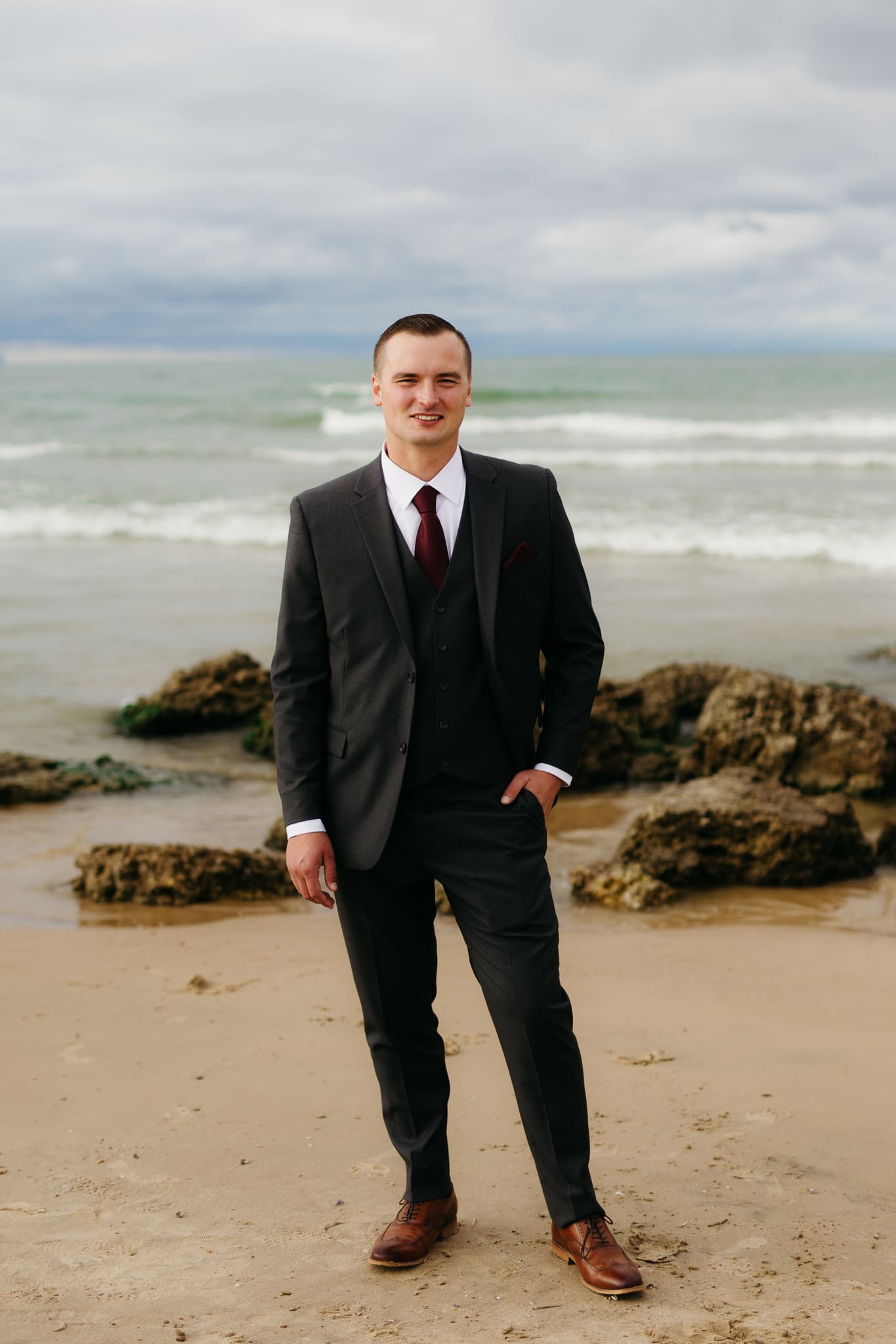 Bride and groom embrace and take couple portraits together along the beach of Lake Michigan during their Indiana Dunes National Park wedding.