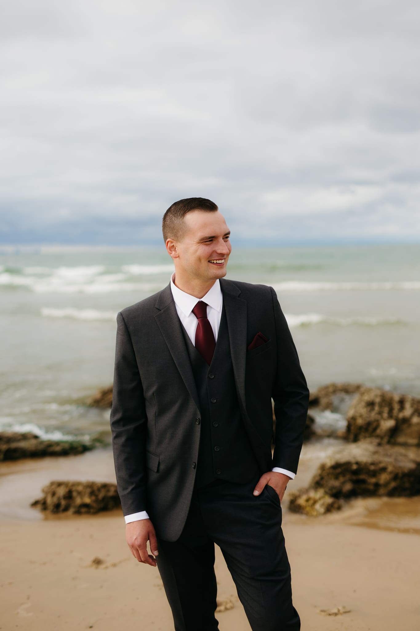 Bride and groom embrace and take couple portraits together along the beach of Lake Michigan during their Indiana Dunes National Park wedding.