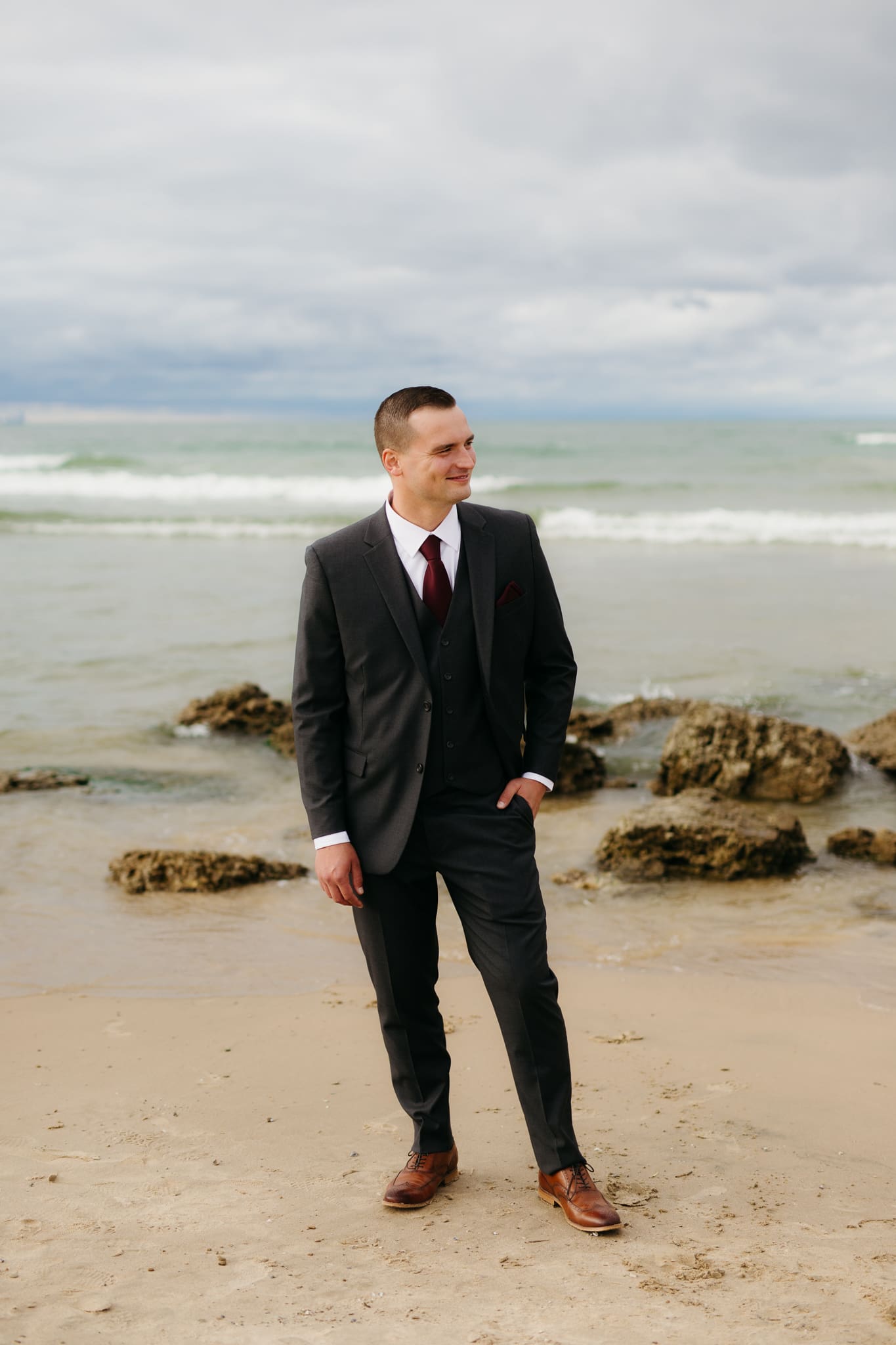 Bride and groom embrace and take couple portraits together along the beach of Lake Michigan during their Indiana Dunes National Park wedding.